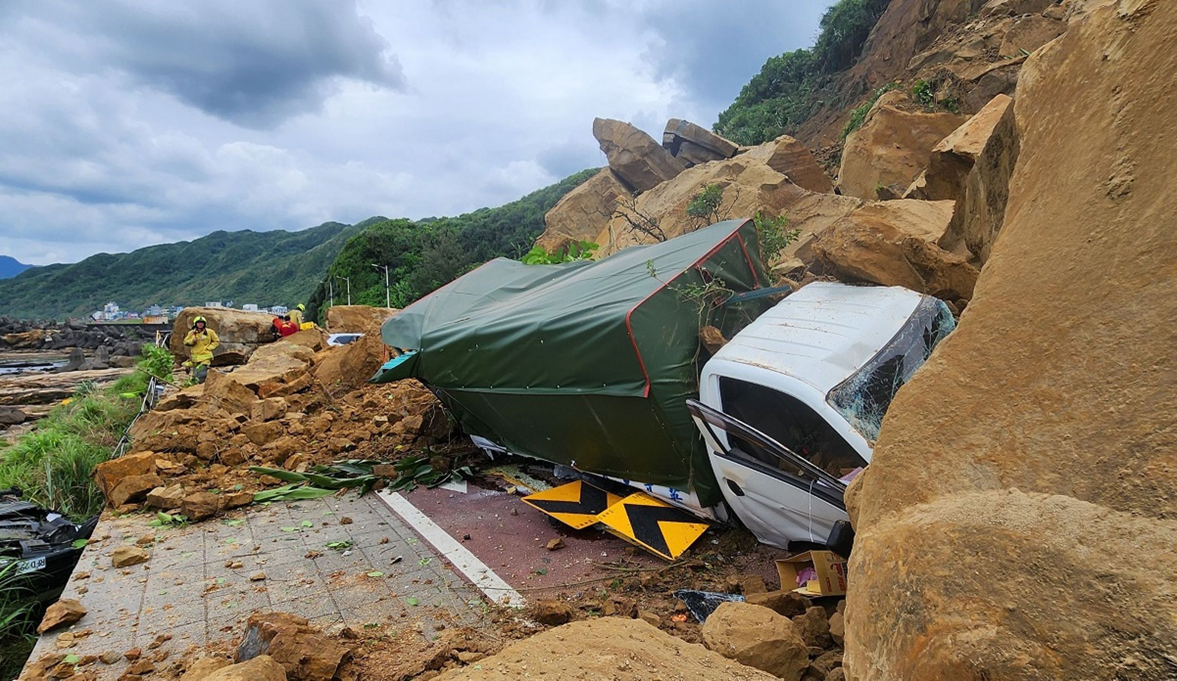 基隆潮境公園路口坍方造成有9部車及1部機車被土石掩蓋受困,目前人員皆已脫困。(基隆市消防局提供)