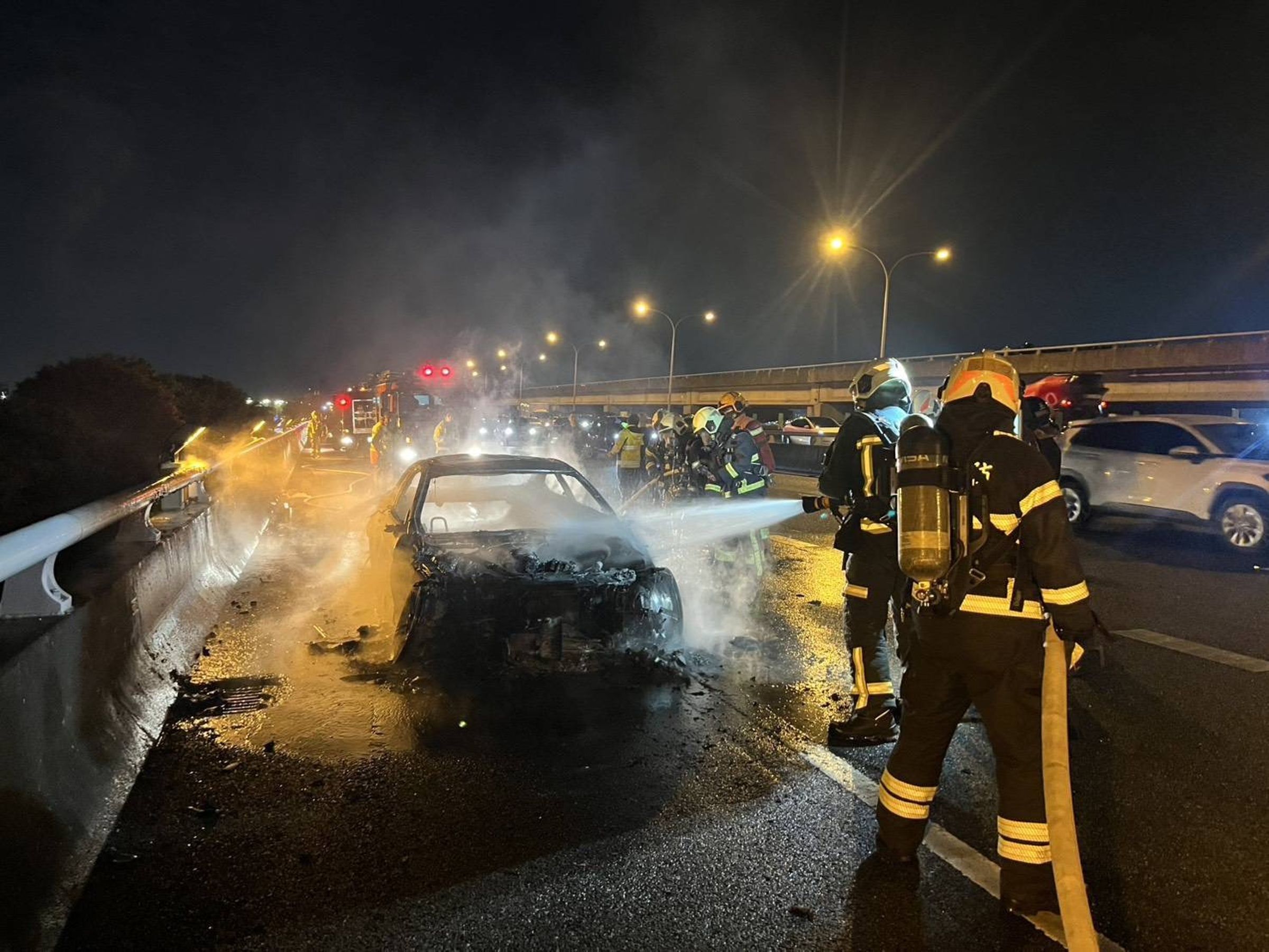 一輛轎車今晚行經國道1號汐五高架堤頂路段時突起火燃燒,整輛車陷入火海。(翻攝畫面)