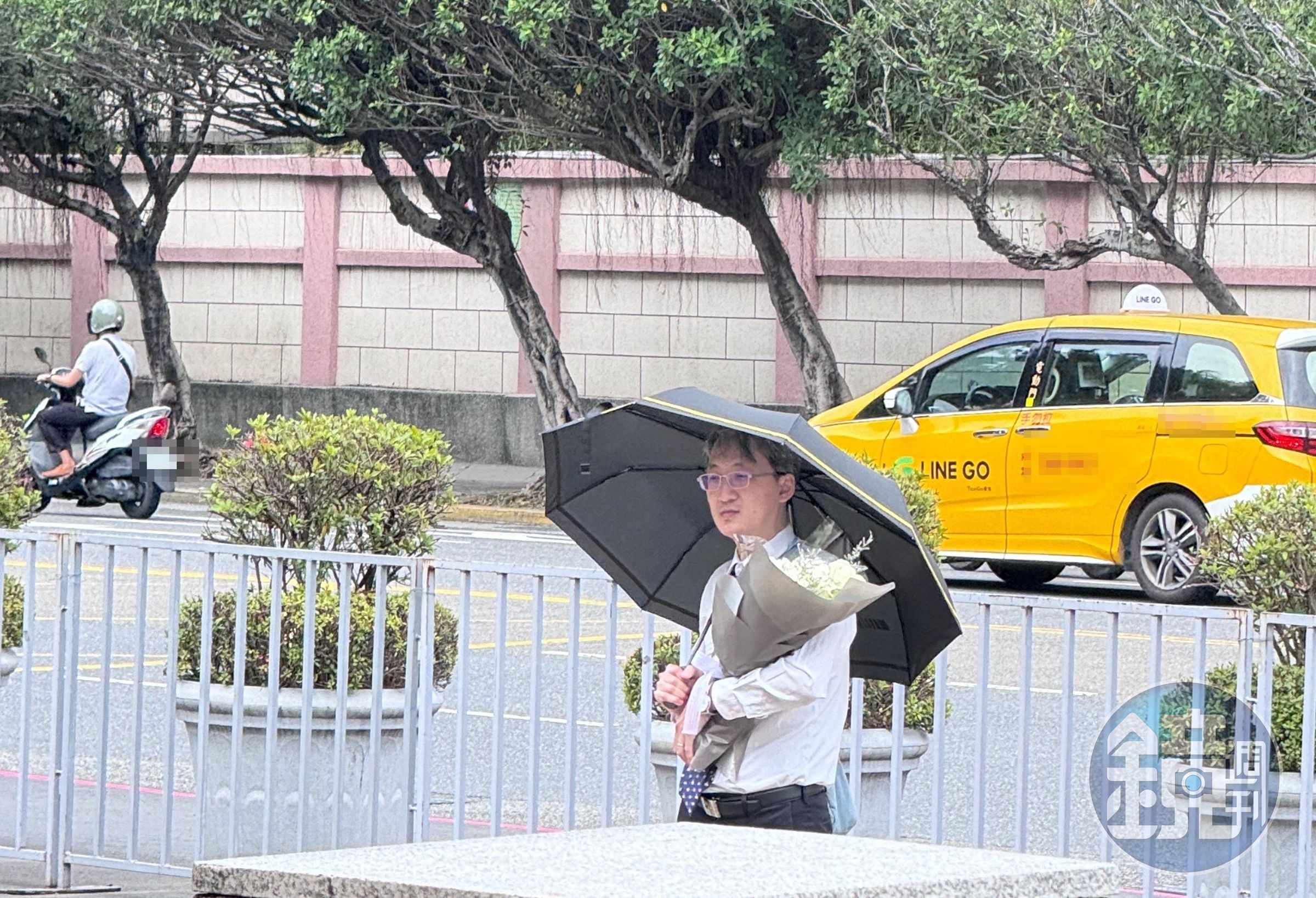 基隆地院法官李岳今現身司法院正門口,手捧白花、撐著黑傘,預計他將會在這站上一天。(本刊資料照)