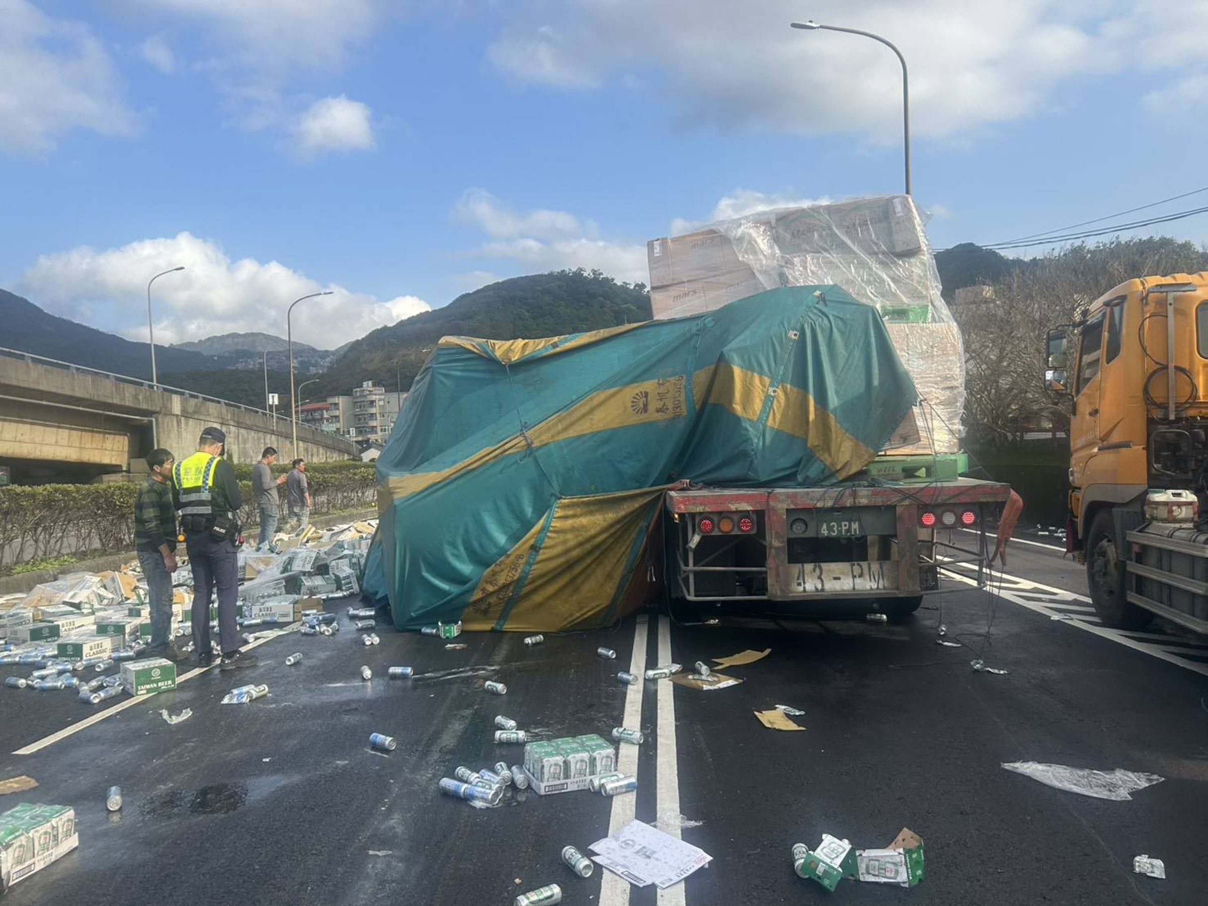 蔡男駕駛的曳引車因綑綁不實，導致車上的罐裝啤酒散落路面。（翻攝畫面）