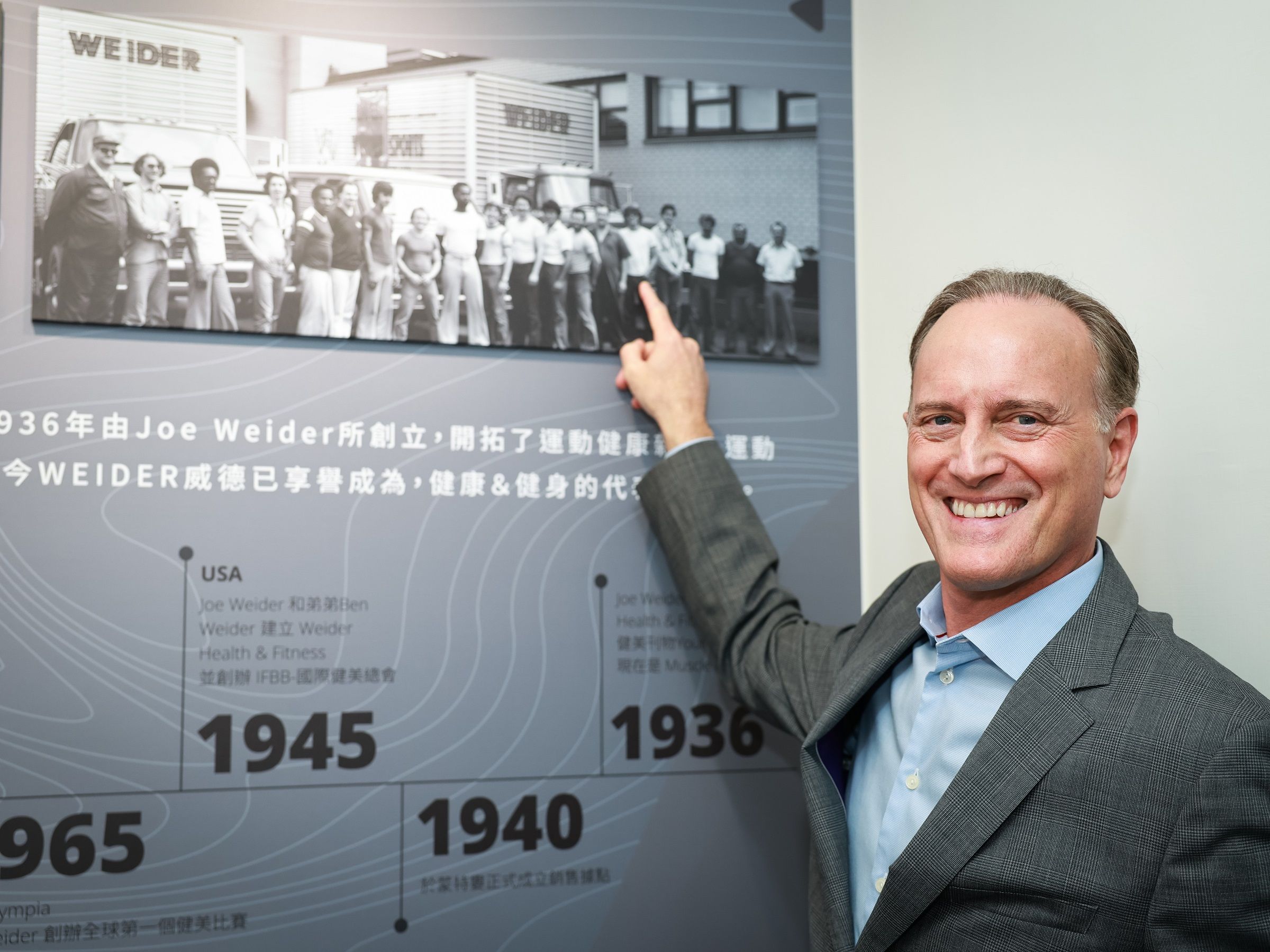 董事長Eric手指照片中年輕的自己,分享在威德自基層做起、贏得員工肯定的經歷。(威德提供)