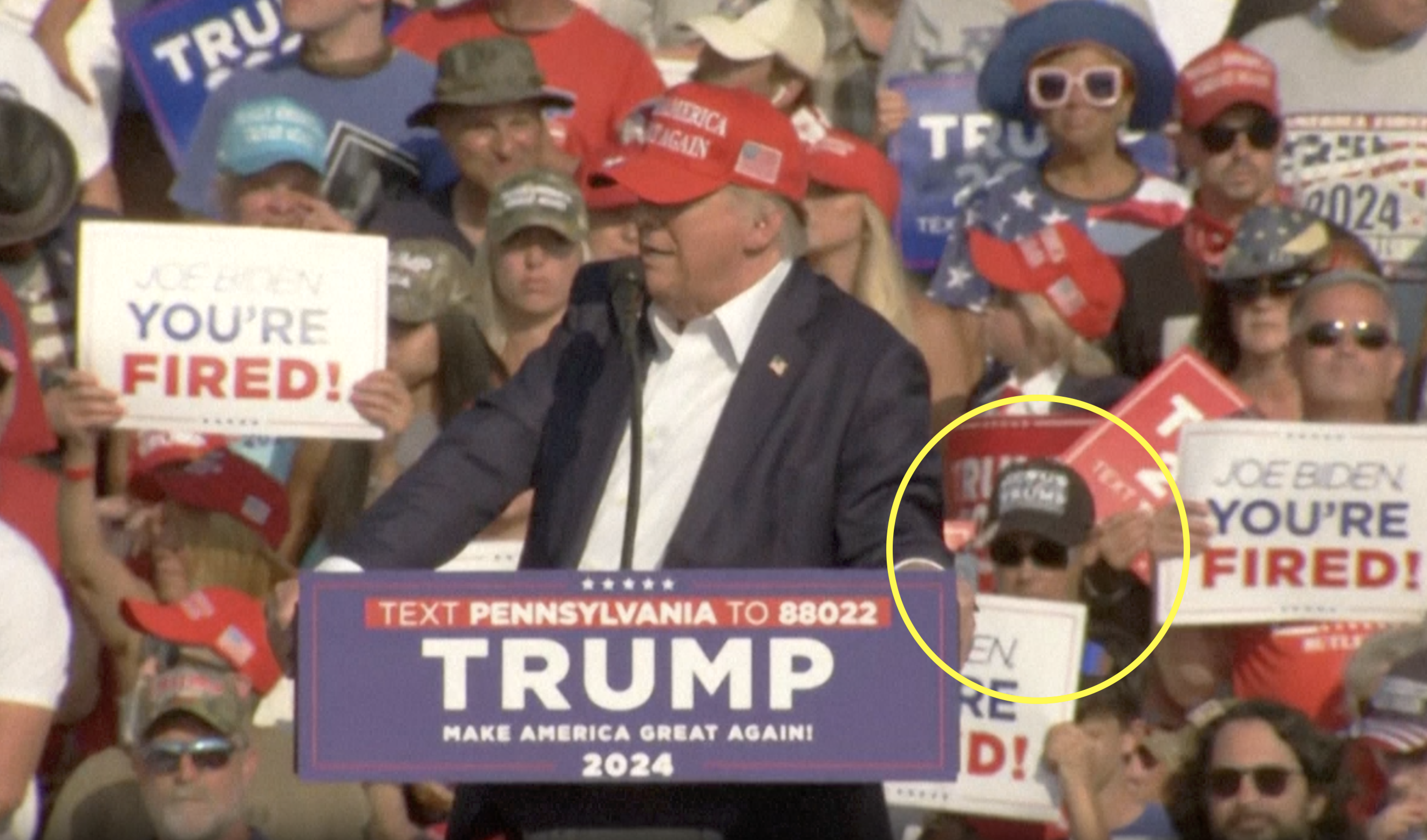 川普遭槍擊時,後方的白衣女子(黃圈處)行為異常,掀起網路熱議。(翻攝畫面)