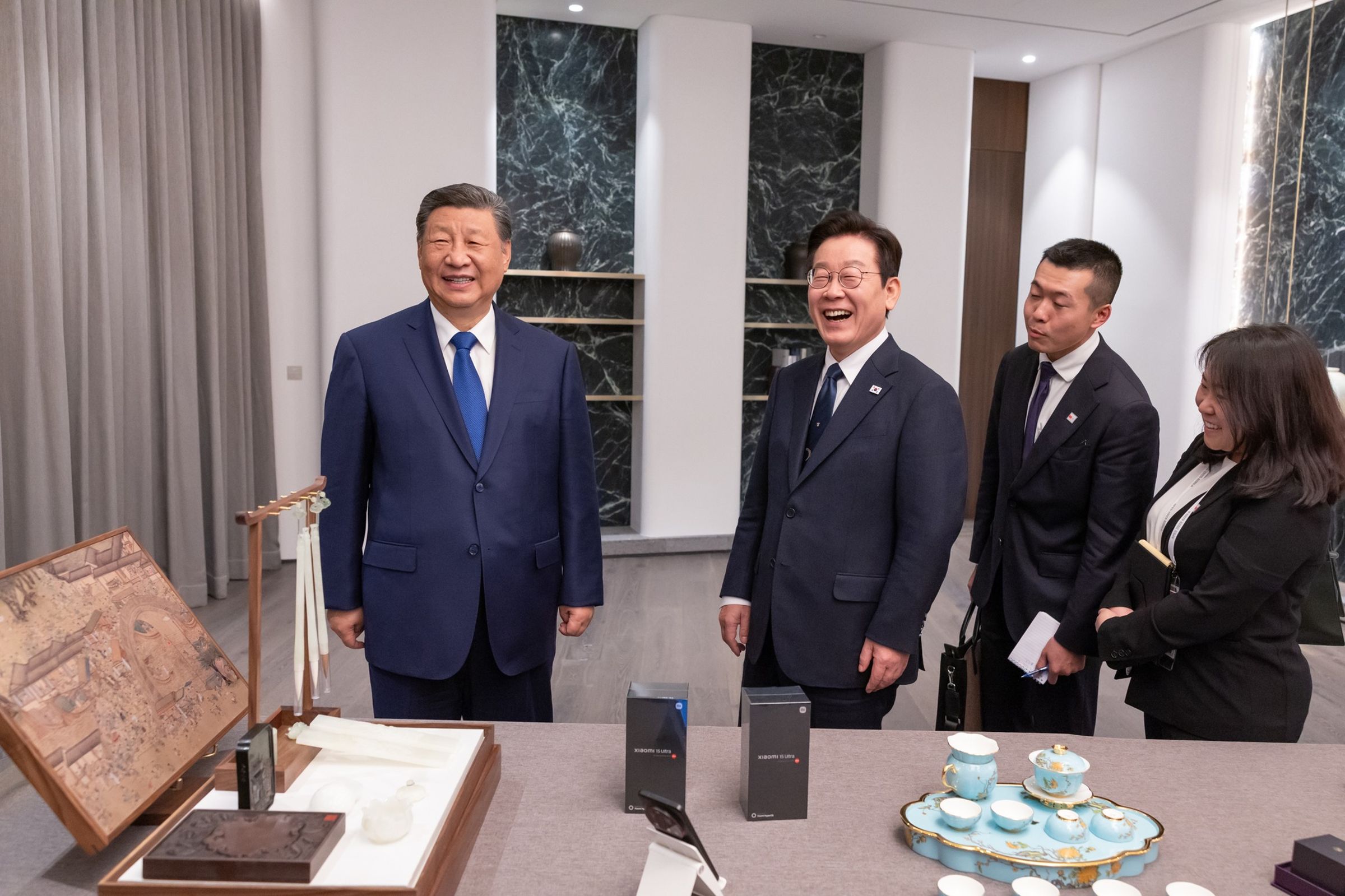 李在明(左2)收小米手機,開玩笑問「安全嗎?」習近平(左1)幽默回應。(翻攝自이재명臉書)