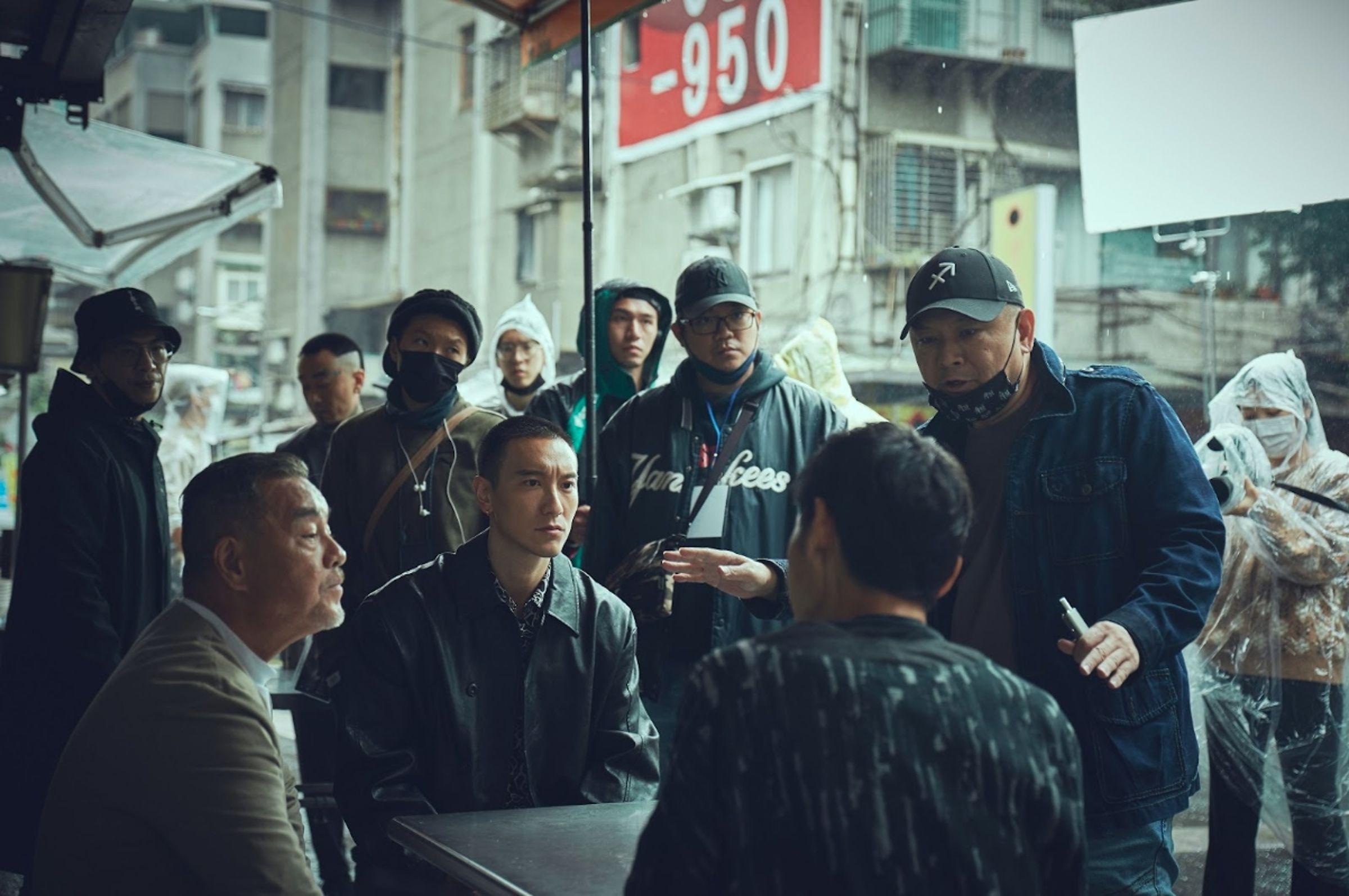 監製張威縯（前排右1）在拍攝現場與演員龍天翔（前排左1）、王陽明（前排左2）討論。（曼尼娛樂提供）