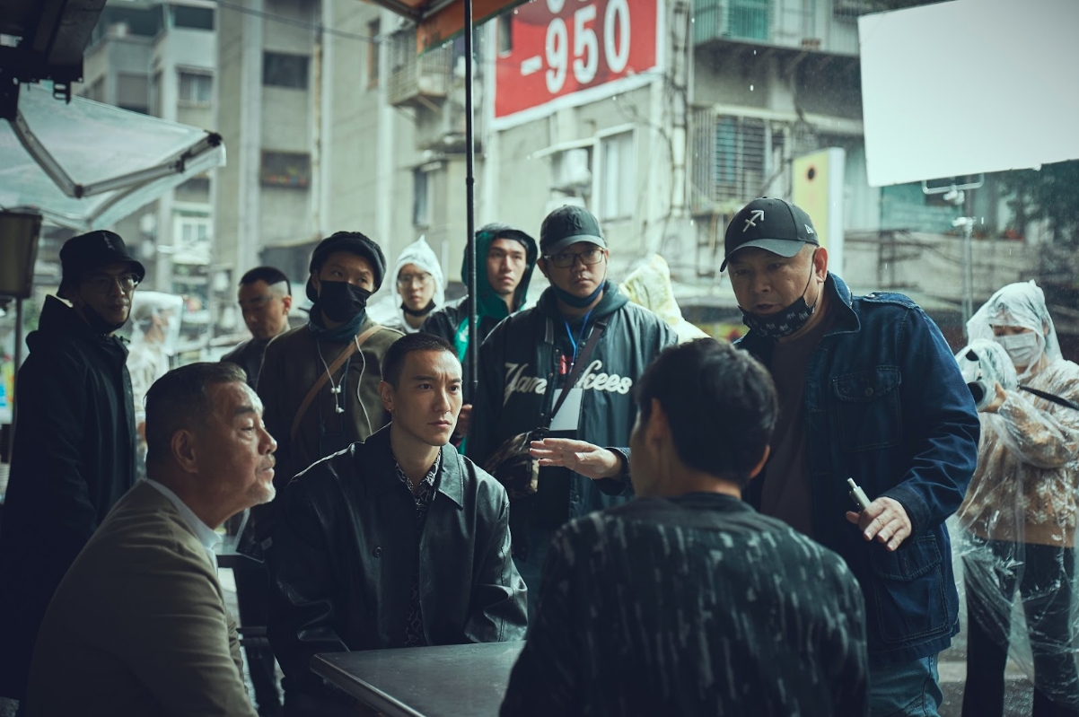 監製張威縯（前排右1）在拍攝現場與演員龍天翔（前排左1）、王陽明（前排左2）討論。（曼尼娛樂提供）