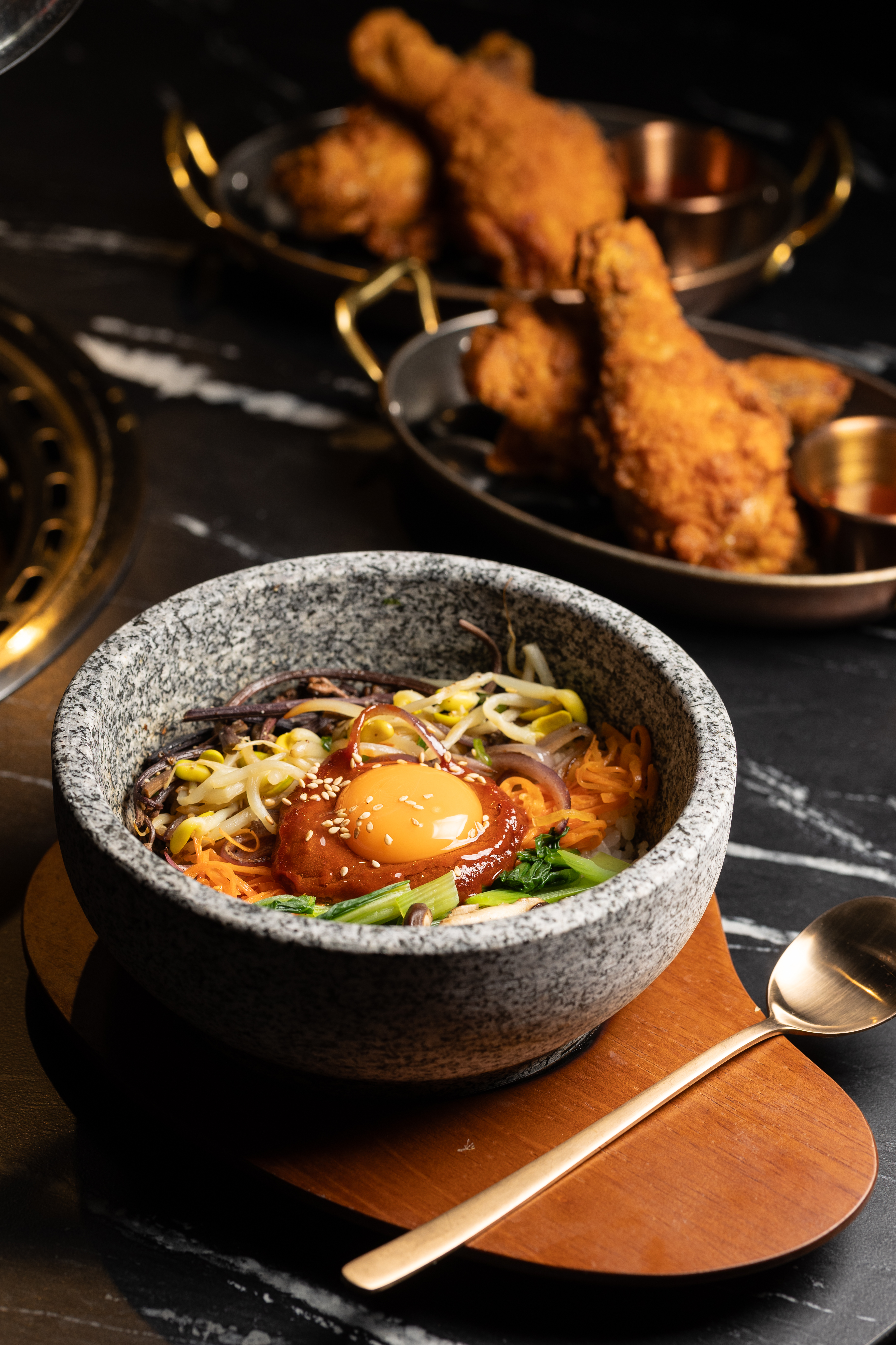 「爆炒和牛舌石鍋拌飯」（前，458元／份）與「主廚韓式炸雞腿」（後，238元／2隻）都是韓劇場景裡讓人一看就想點的經典美味。