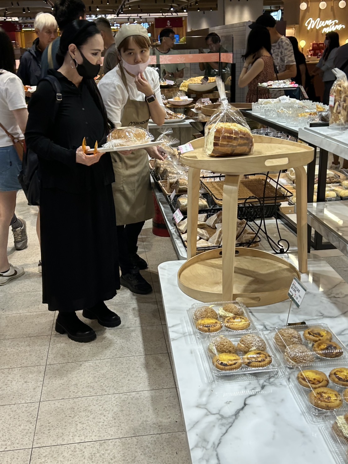 潘越雲買麵包時店員熱心介紹，白髮男好友在後方。（讀者提供）