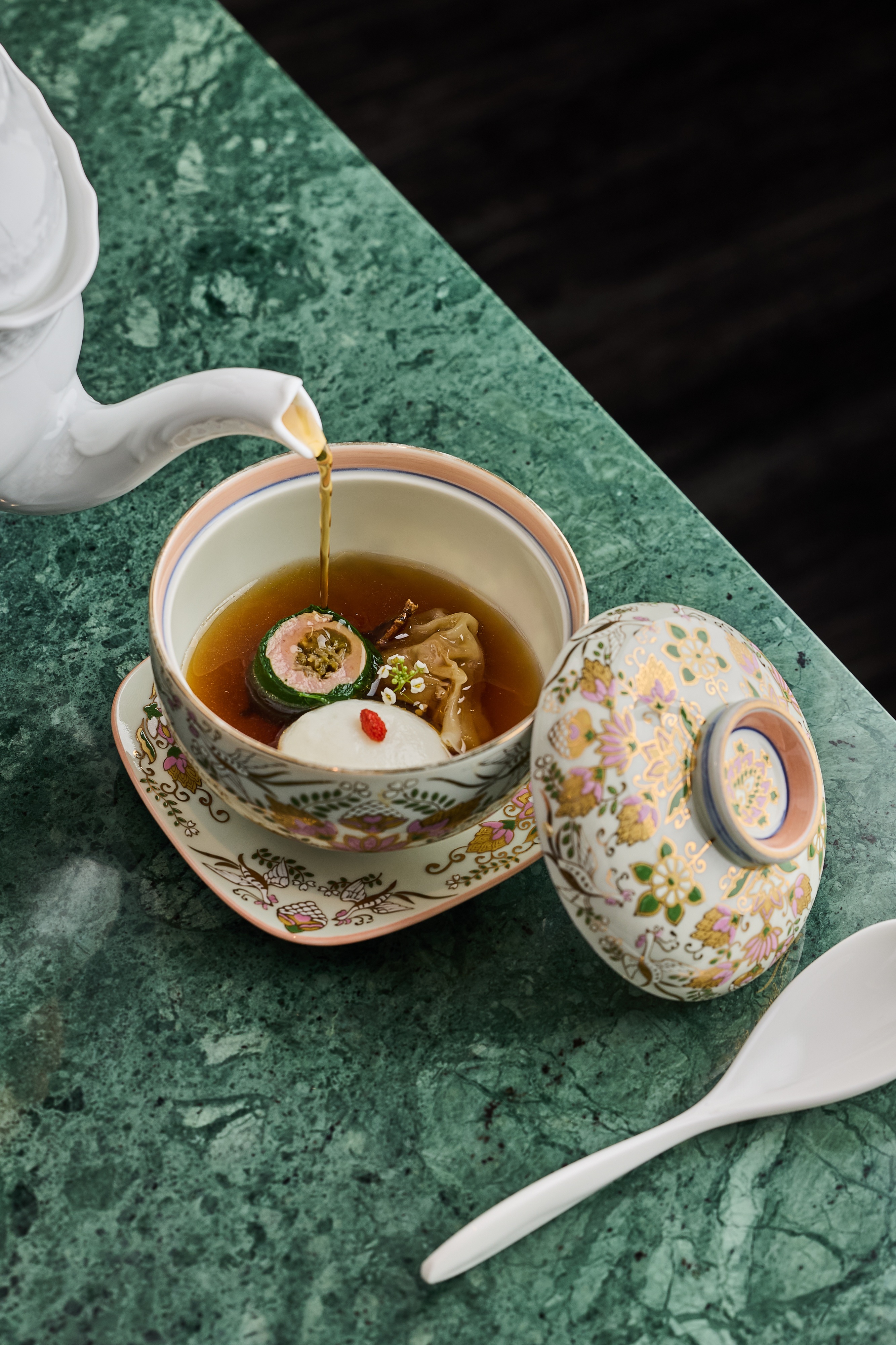「薑母、鴨、魚丸」做法繁複，先將老薑、黑麻油煸香，續入鴨腿、鴨翅炒香後，再放入當歸、川芎、枸杞、紅黑棗和雞豬高湯慢熬6小時後取澄清鴨湯，搭配當歸、參藥酒和東星斑製成的手打當歸魚丸。還有以菠菜包捲鴨胸肉及酸菜做成的酸菜鴨肉捲。（aMaze心宴提供）
