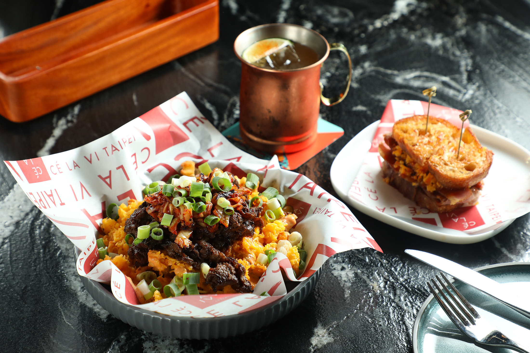 位於台北微風南山48樓「boon現代韓式餐酒館」的「韓式烤牛肉起司薯條」（左前，450元／份）滋味濃郁，是「Moscow Mule」（中後，350元／杯）的最佳拍檔；「煙燻牛肉三明治」（右，350元／份）以切達起司與泡菜糖醋醬畫龍點睛。