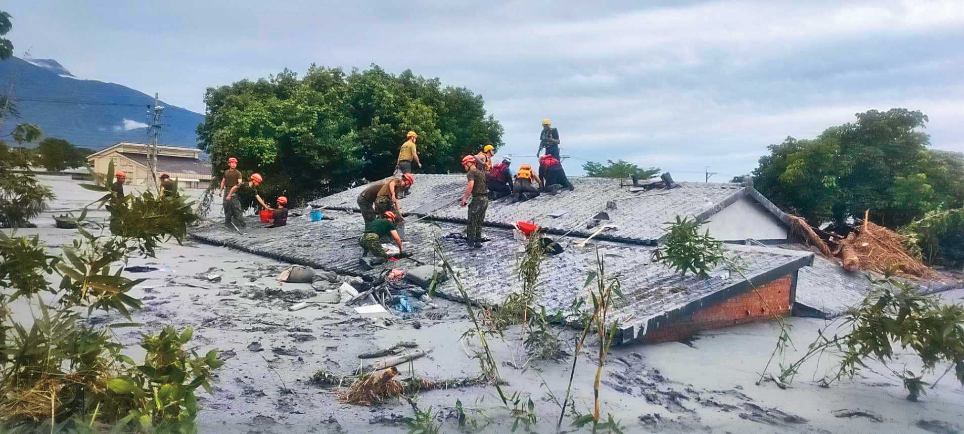 黑色土石泥流淹沒民宅，只剩屋頂可見，淤積厚度近3公尺。（翻攝花蓮縣政府臉書）