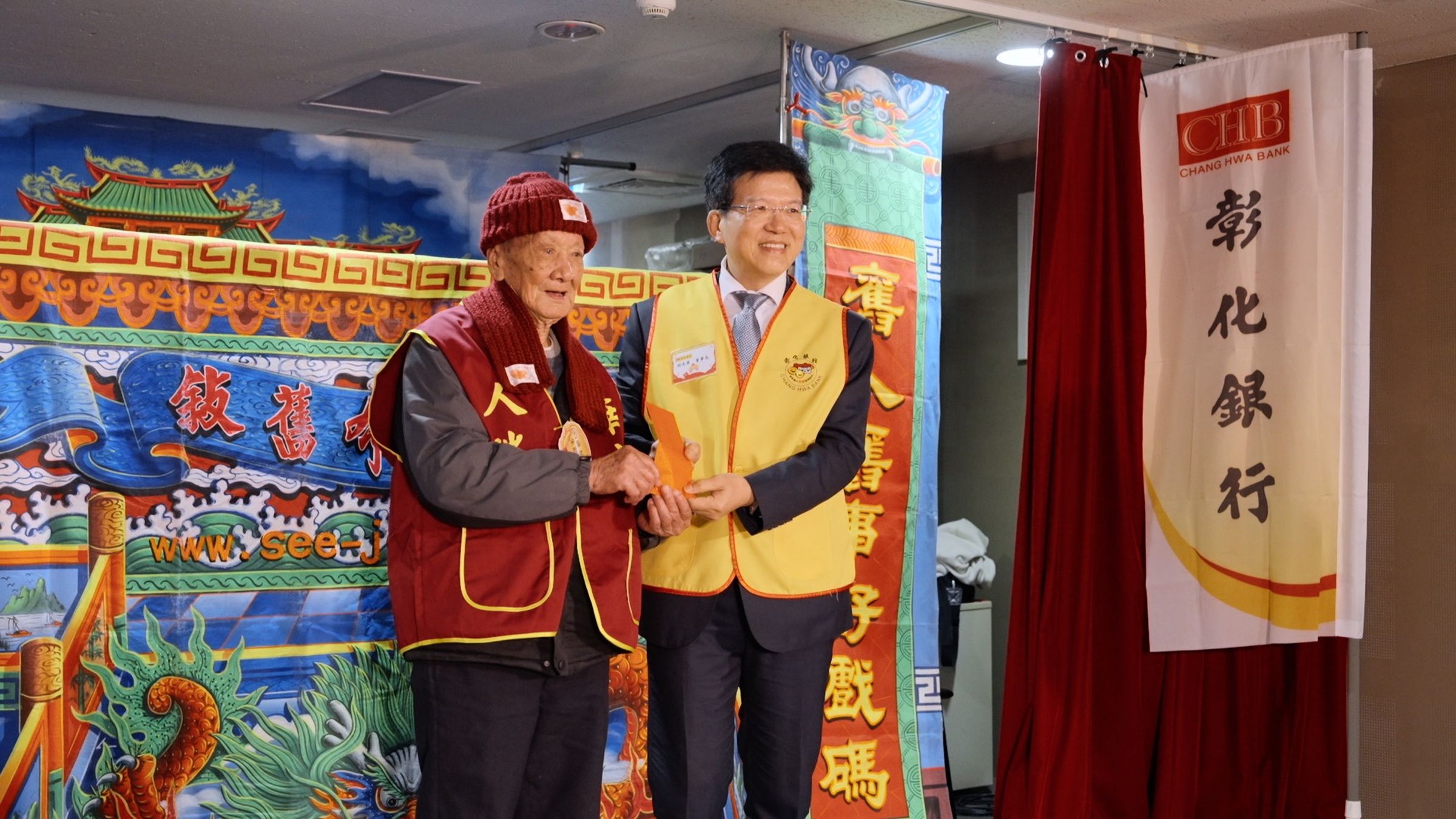彰化銀行胡光華董事長(圖右)親自贈送象徵福氣的紅包,給予今年101歲的百歲人瑞朱爺爺(圖左),祝福長壽健康。