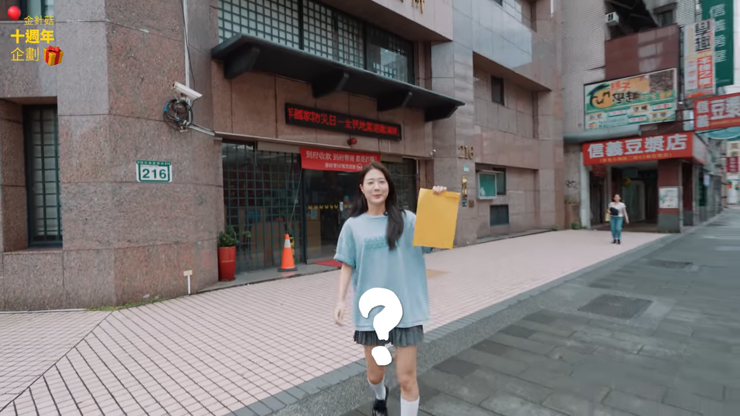 百萬YouTuber網紅金針菇從北市派出所走來，神祕兮兮地拿著一份文件。（翻攝自YouTube 韓勾ㄟ金針菇 찐쩐꾸）