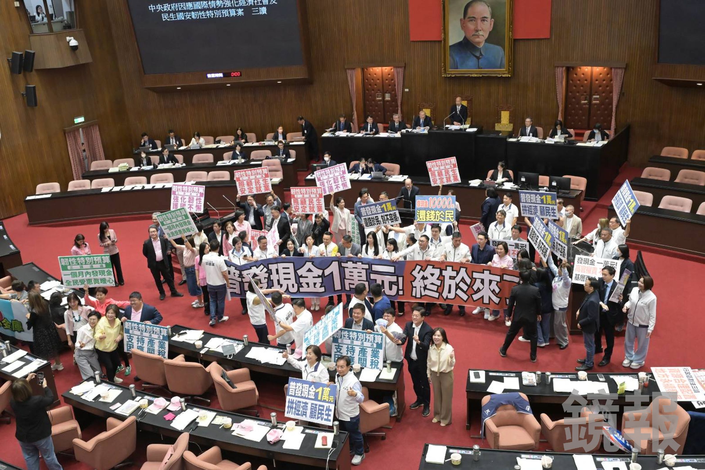 立法院今三讀通過韌性特別預算，確定將普發現金1萬元，各黨團開心拍照，羅明才又拿起1萬元在手上揮舞。（鏡報林煒凱）