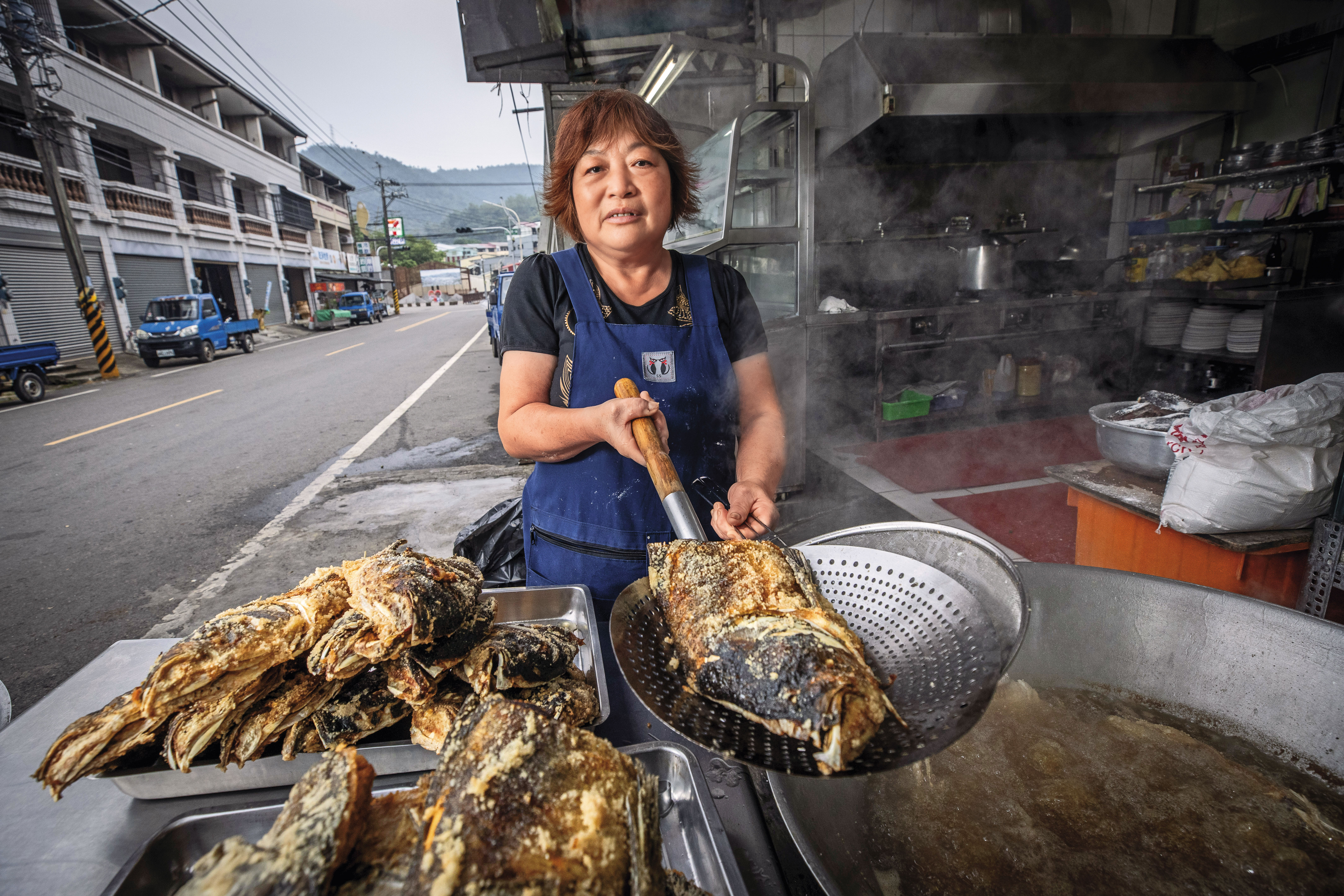 清晨5點多，砂鍋魚頭一條街仍冷清，江明苓隻身在店前馬路邊炸魚頭，10度低溫下卻大汗淋漓。