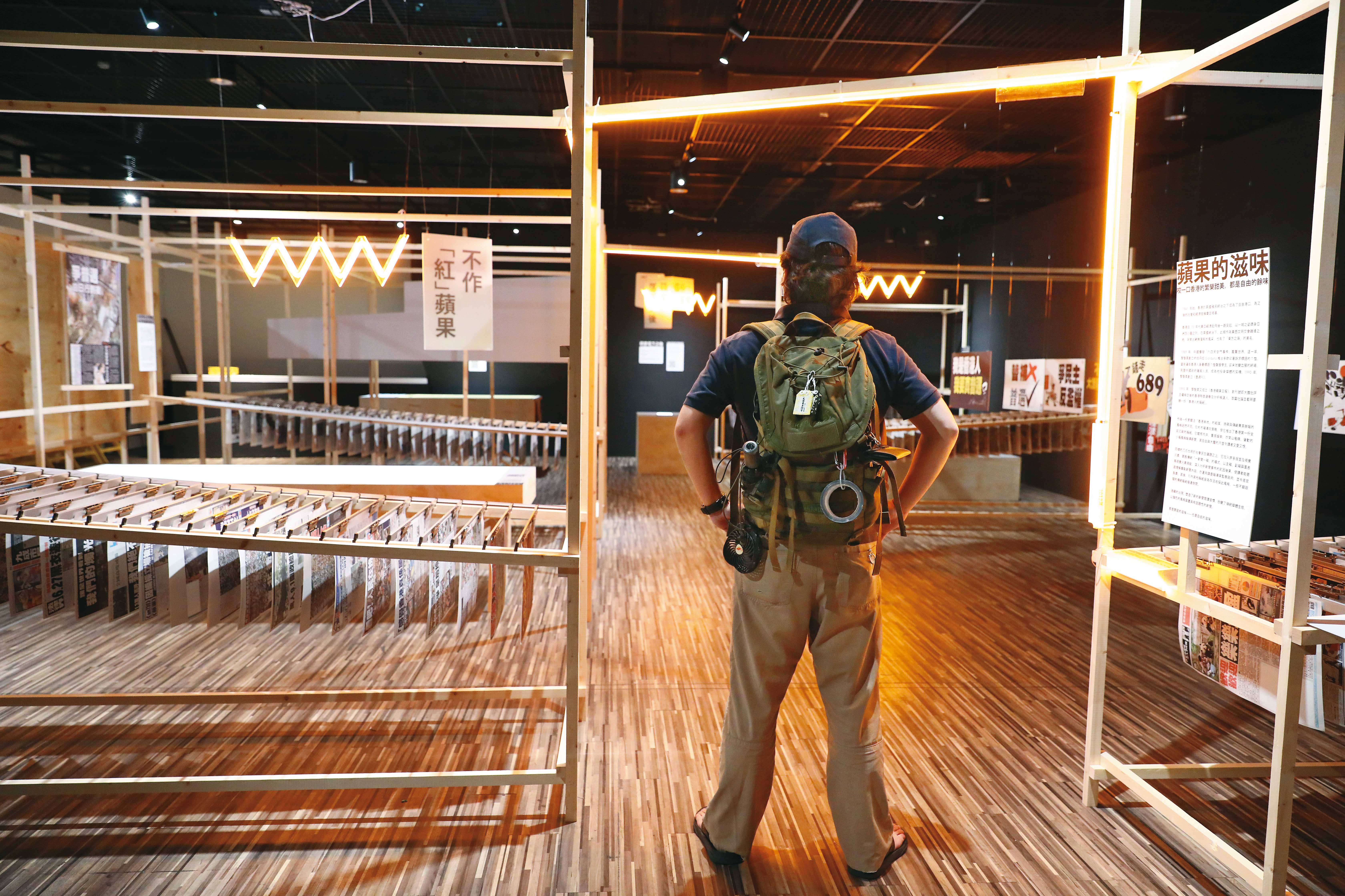 許多港人逃到台灣，卻擔心在港家人受累。圖為2022年一名港人在台灣出席文總「備份一座城市」特展，現場展出多份絕版的香港《蘋果日報》。（杭大鵬攝）