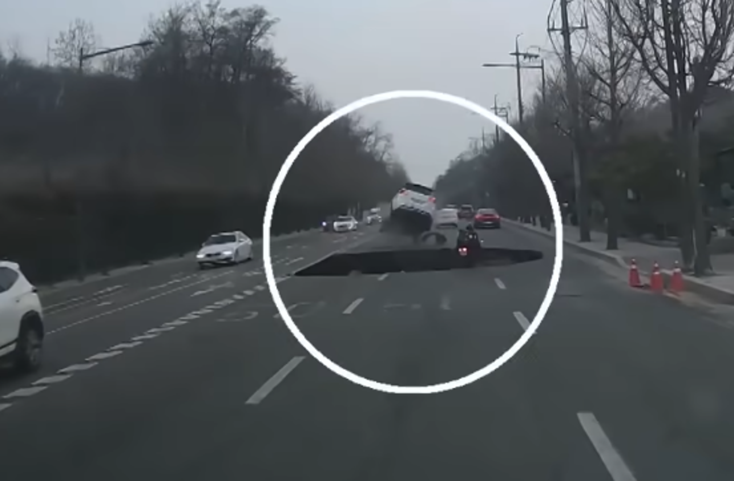前方白色轎車幸運閃過,但後方騎士閃避不及,掉入天坑。(翻攝自YouTube頻道연합뉴스TV)