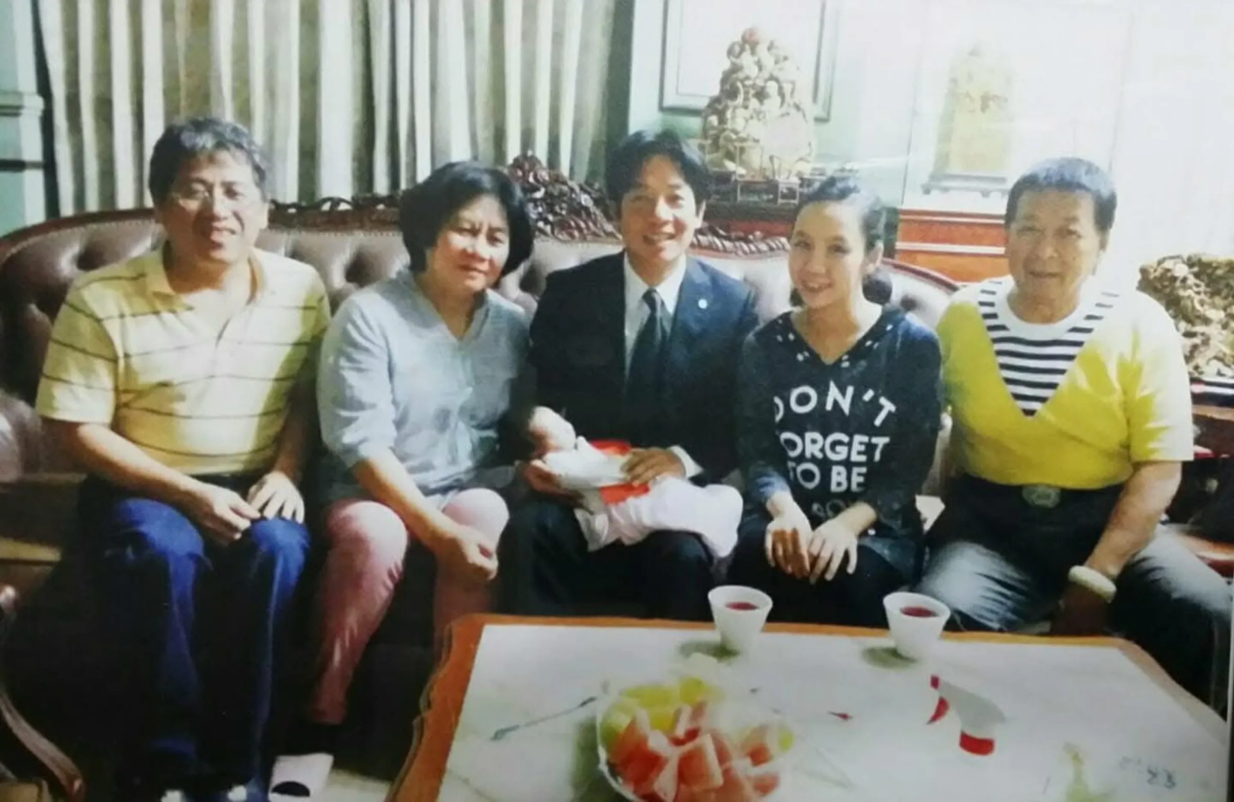 姜厚任女友童芯父親、綠營輔選大佬陳宏明(右起)、童芯、賴清德、陳苡孋的媽媽以及通靈老師。賴清德手中抱著童芯的孩子,照片推估拍攝於賴清德擔任台南市長任內。(《鏡報》提供)