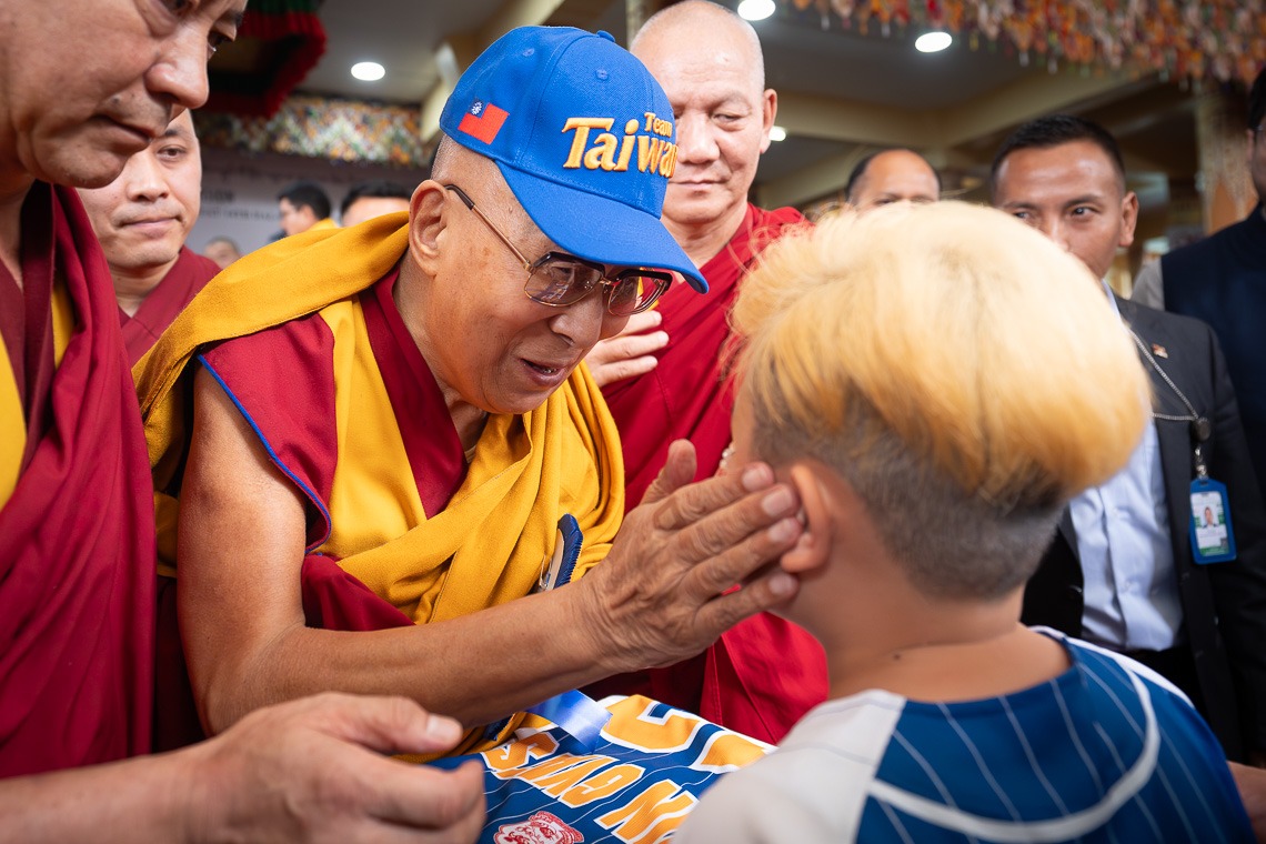 達賴喇嘛收到印有「Team Taiwan」的帽子與球衣，不僅當場戴上，還親切撫摸獻禮小男孩臉龐。（翻攝自རྒྱལ་བ་རིན་པོ་ཆེ།臉書）