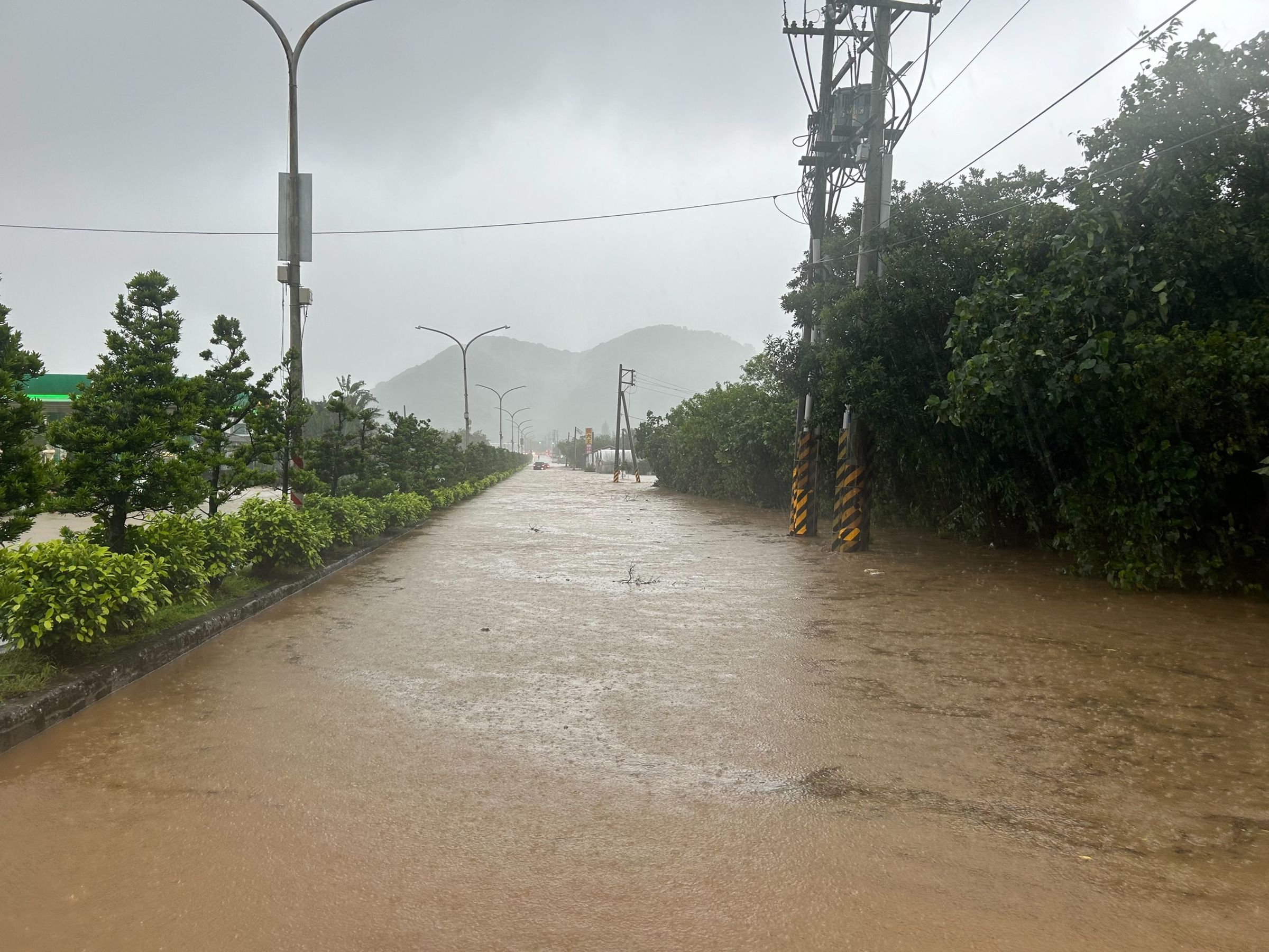 新北市往金山、萬里路段因溪水暴漲,黃色的泥水淹至馬路。(取自新北市石門區公所臉書)