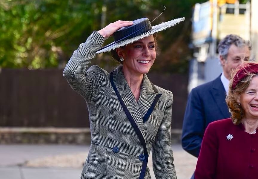 凱特王妃戴上黑白千鳥格寬邊草帽現身，面對強風一手按住帽緣。（翻攝X@sarahdiaryz）