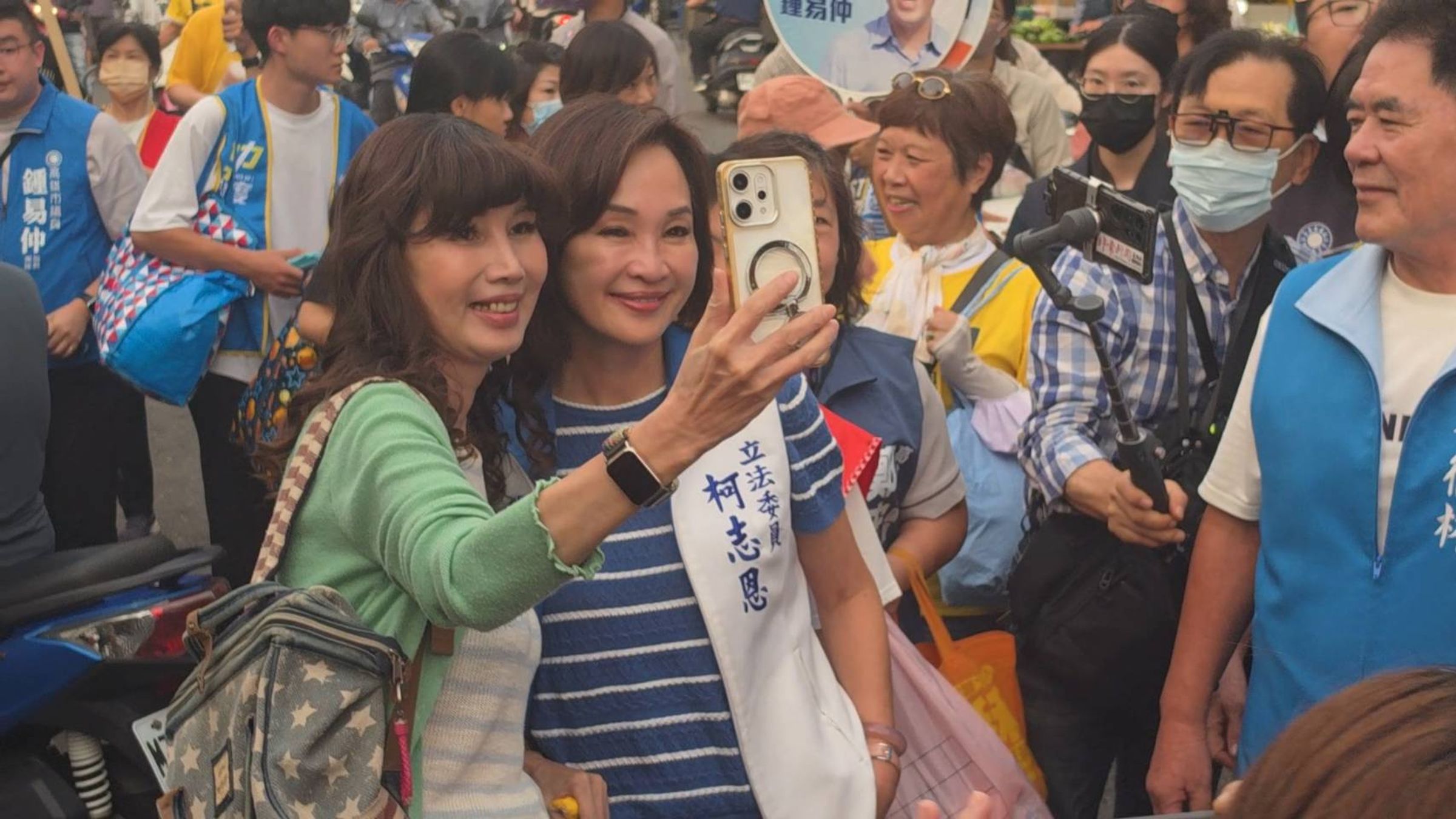 女性支持者與柯志恩合照、擁抱,另有市場員工向老闆「請假」,離開攤位上前合影。
