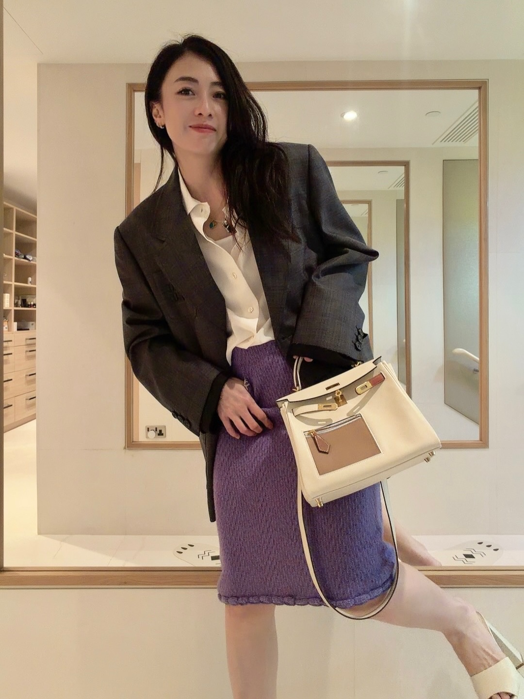 甘比身穿自創品牌KUUKee的紫色針織裙，搭配愛馬仕Kelly 25 Colormatic拼接凱莉包，身後還可見大片鏡面裝潢。（翻攝kimbeechan_official IG）