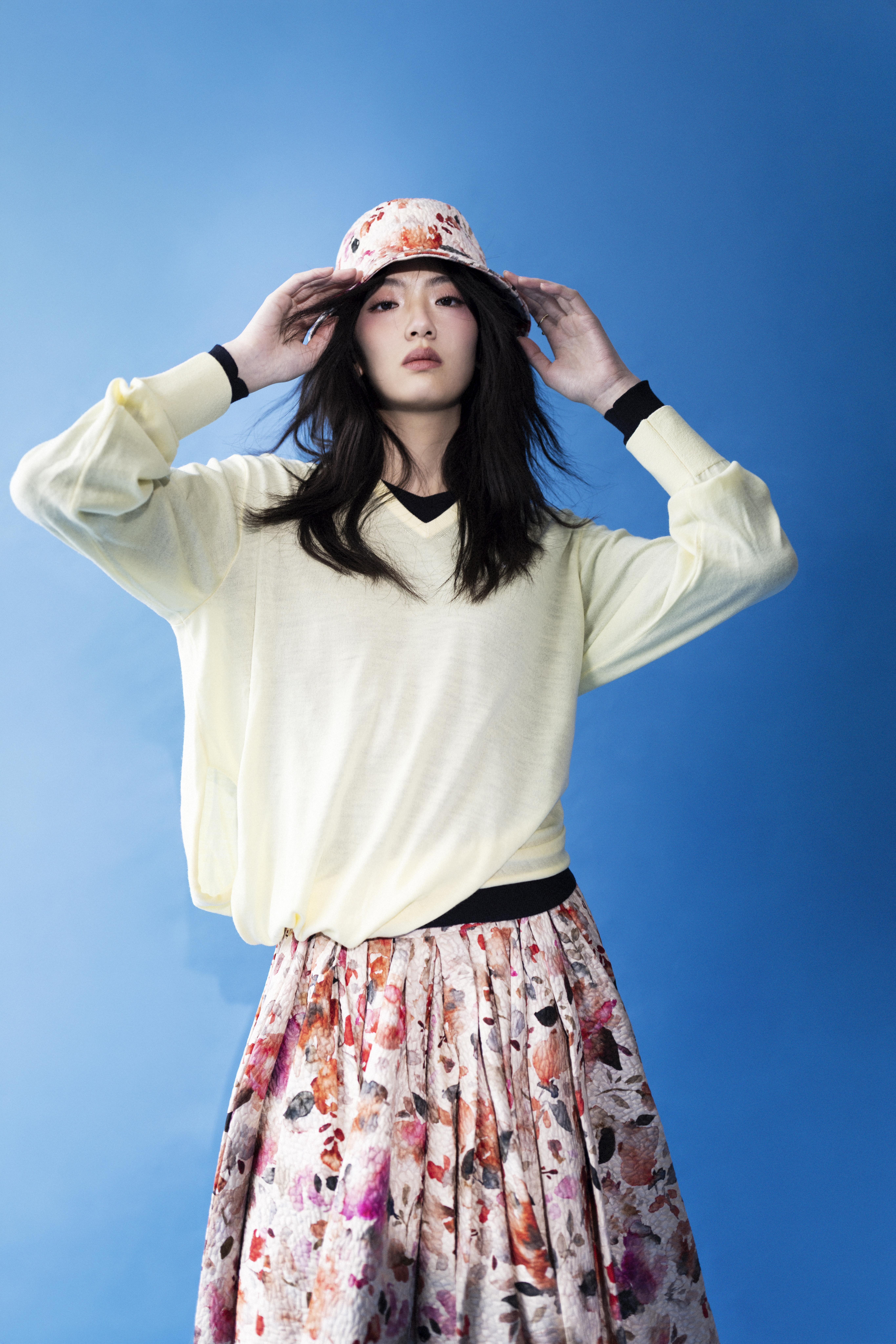 黃色縲縈混紡上衣 NT$38,000 by LOEWE；黑色立領針織衫 價格店洽 by MIU MIU Lorelay；半截裙 價格店洽 by Loro Piana；Zaltana帽子 價格店洽 by Loro Piana Mercy Twist；鑽石戒指 NT$138,000 by Georg Jensen。