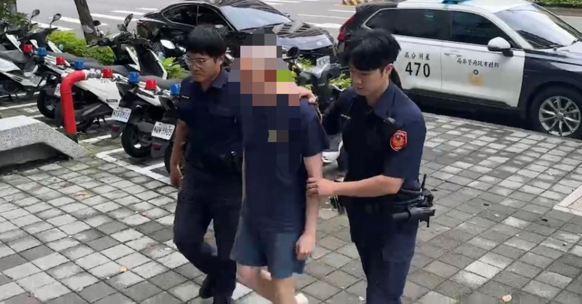 新北市五股區成泰路三段一名光頭黑衣男子在人行道上持槍徘徊,甚至做出拉滑套上膛動作並隨意咆哮,嚇壞早起上班上課的民眾。(翻攝畫面)