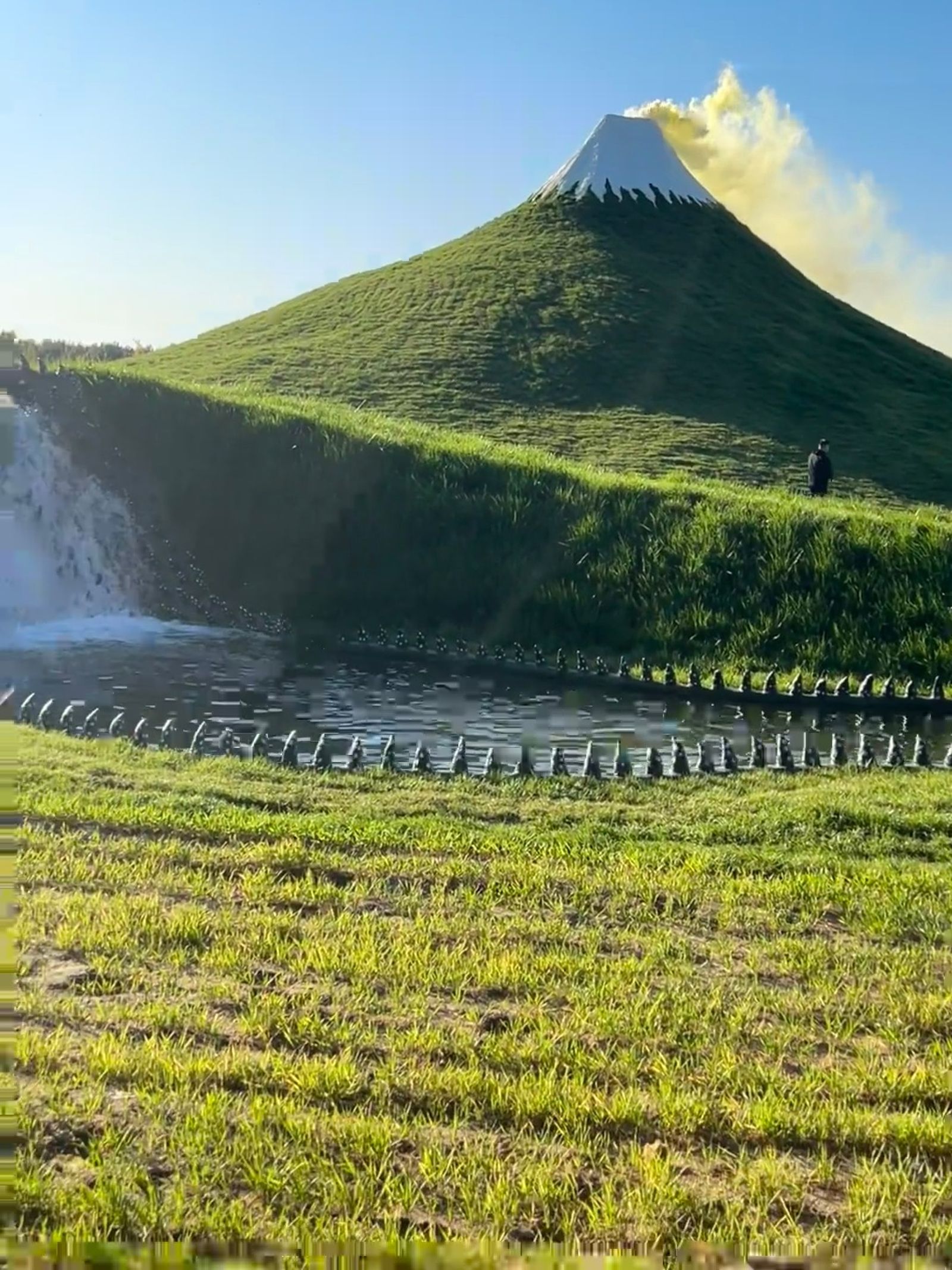 該樂園以人工草皮覆蓋山丘、白色塗料模擬雪頂，打造山寨日本富士山。（翻攝畫面）