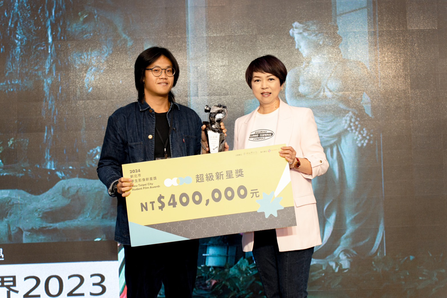 龔雅雯副祕書長（右）與超級新星獎《環遊世界2023》得主合影（由攝影陳頤芳代領）。（新北市文化局提供）