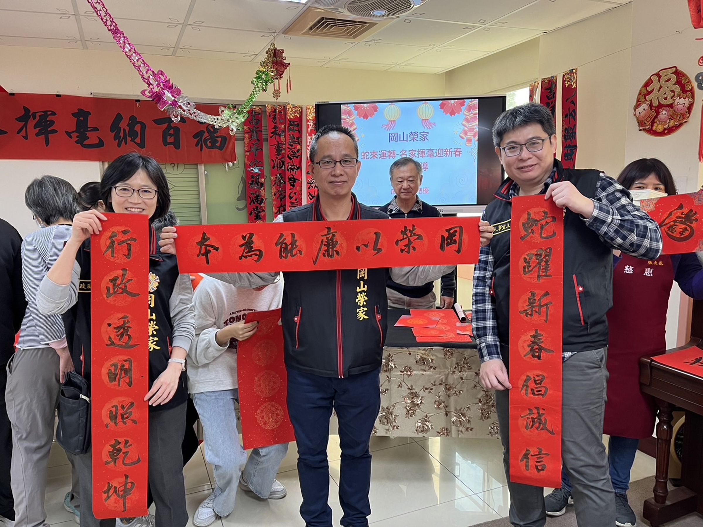 岡山榮家舉辦「蛇來運轉—名家揮毫迎新」活動,由家主任李文國(中)親自主持。(岡山榮家提供)