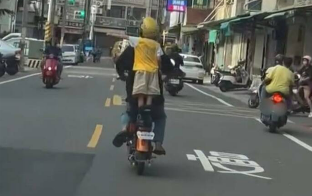 有網友在高雄市大社區路上直擊1名男子騎電動單車，有1名兒童站在後座。（翻攝畫面）