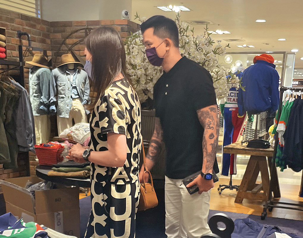 劉怡萱（左）和黃育仁（右）逛街遭直擊，男方耐心陪著挑衣服，亦步亦趨跟在她旁邊。（讀者提供）