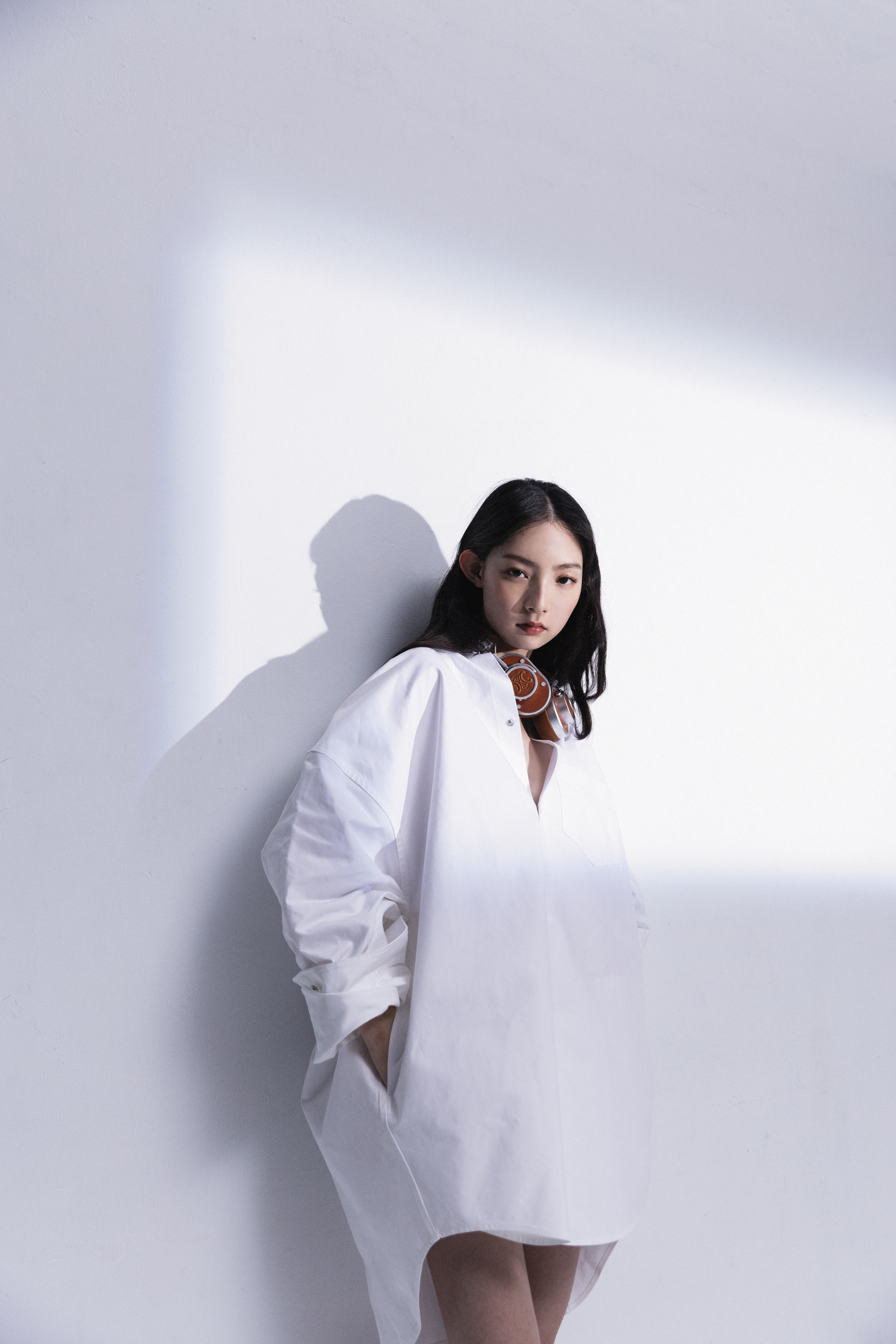 寬鬆白色襯衫 NT$47,400 by BALENCIAGA；棕色TRIOMPHE壓花天然牛皮革耳機 NT$31,000 by CELINE BY HEDI SLIMANE。