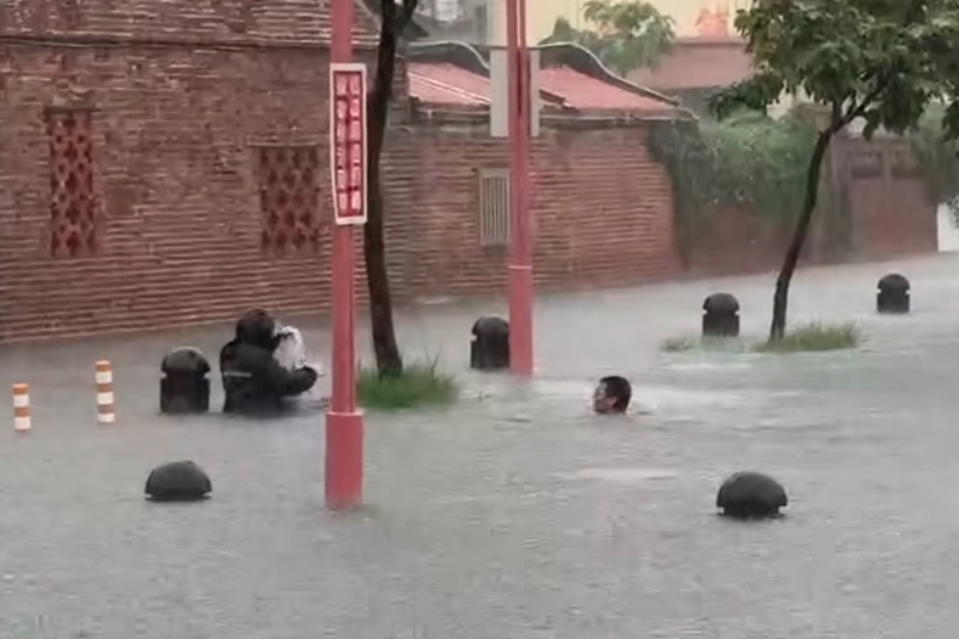 鹿港公會堂前淹水嚴重，水淹至大腿，卻有3人披著泡棉趁亂游泳戲水，直到有民眾錄影才離開。（翻攝自彰化縣媒體記者協會）