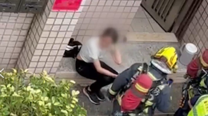 謝女放火後坐在門前哭泣，消防局入屋收拾殘局。（民眾提供）