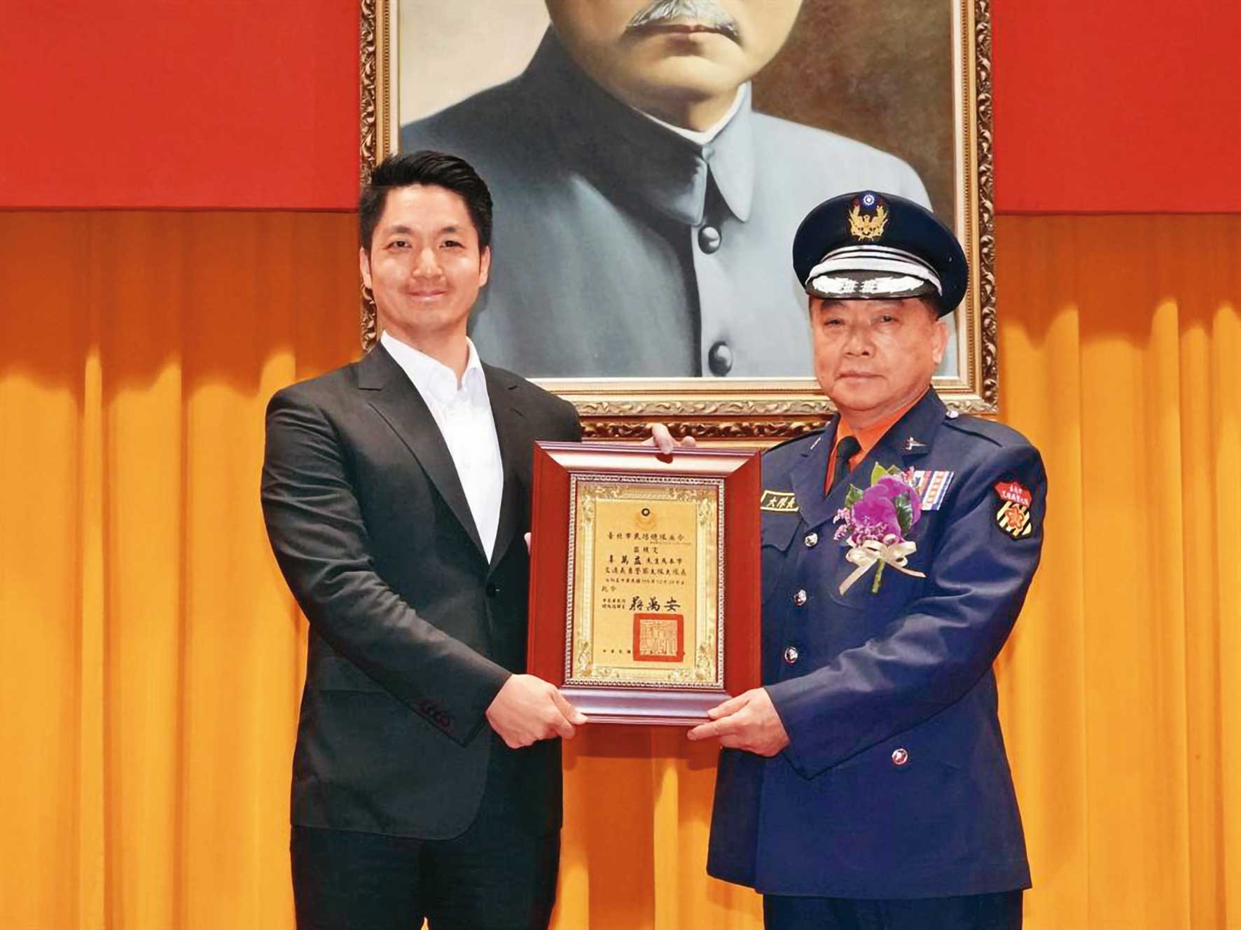 辜萬益（右）升義交大隊長時，曾被檢舉超齡，最後仍從台北市長蔣萬安（左）手中接下聘書，順利就任。（翻攝畫面）