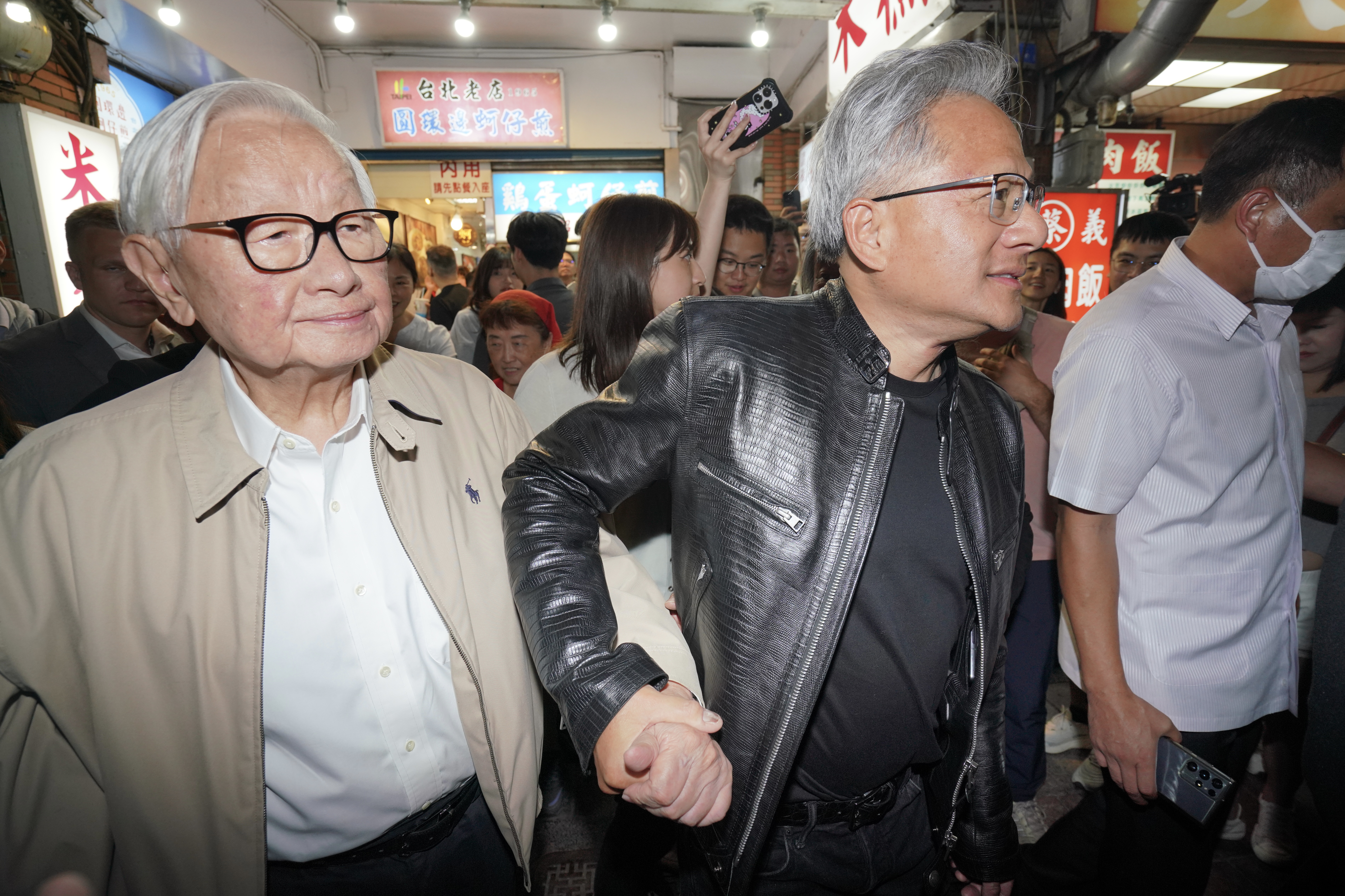今年5月，黃仁勳（右）攜手張忠謀逛夜市，兩人緊密的「晚餐」關係並非僅限於台灣小吃，張忠謀在自傳中揭開台積電與輝達如何以一頓披薩晚餐解決雙方爭議。（本刊資料照）