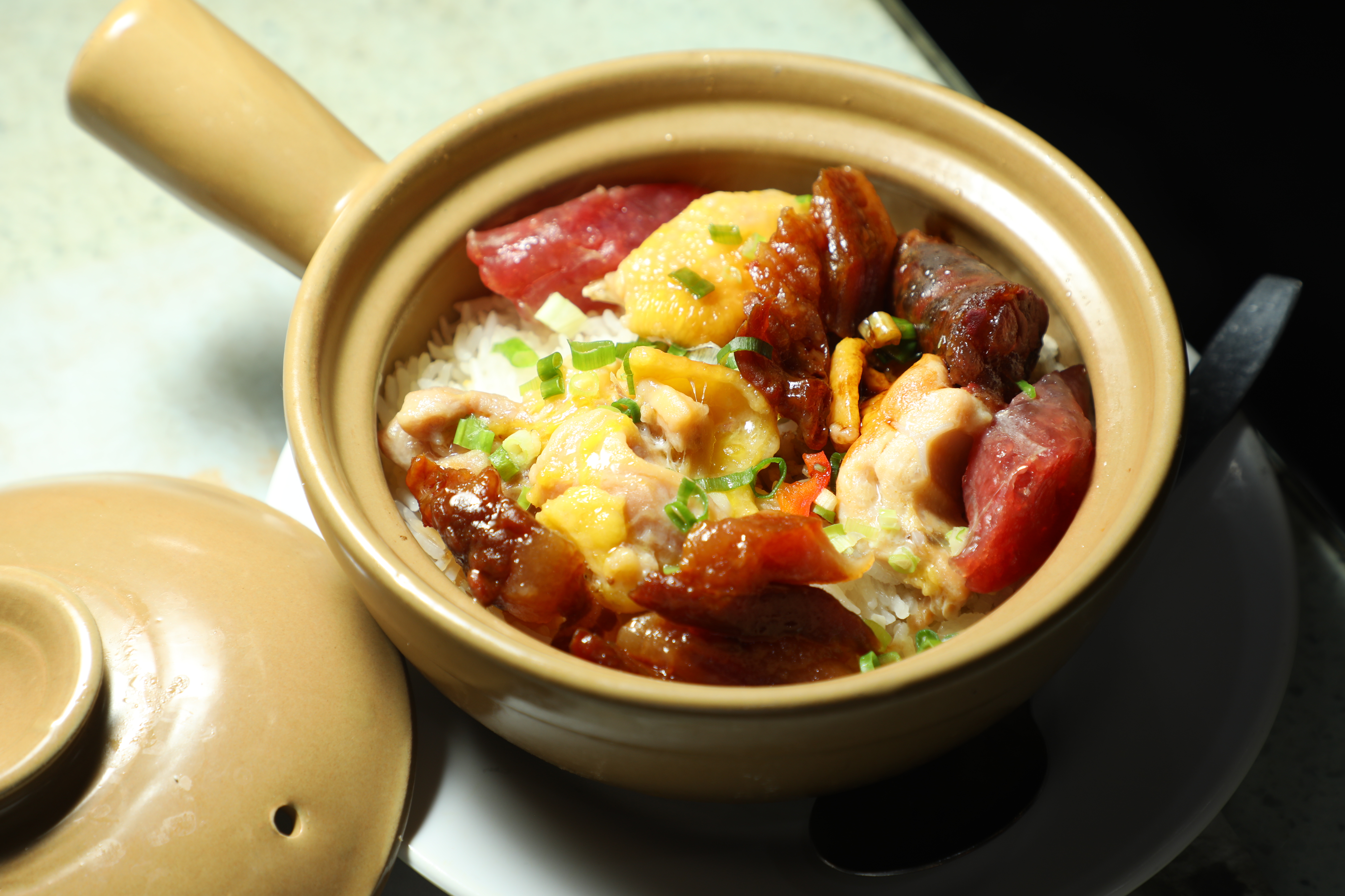 靠煲仔飯打響名號的「嚐囍煲仔小菜」，標榜以火山石取代傳統炭火煲飯，有白鱔、滑雞、臘味、窩蛋牛肉餅等30多種選擇，可依口味排列組合，圖為「臘味滑雞飯」。（港幣108元／份，約NT$408）