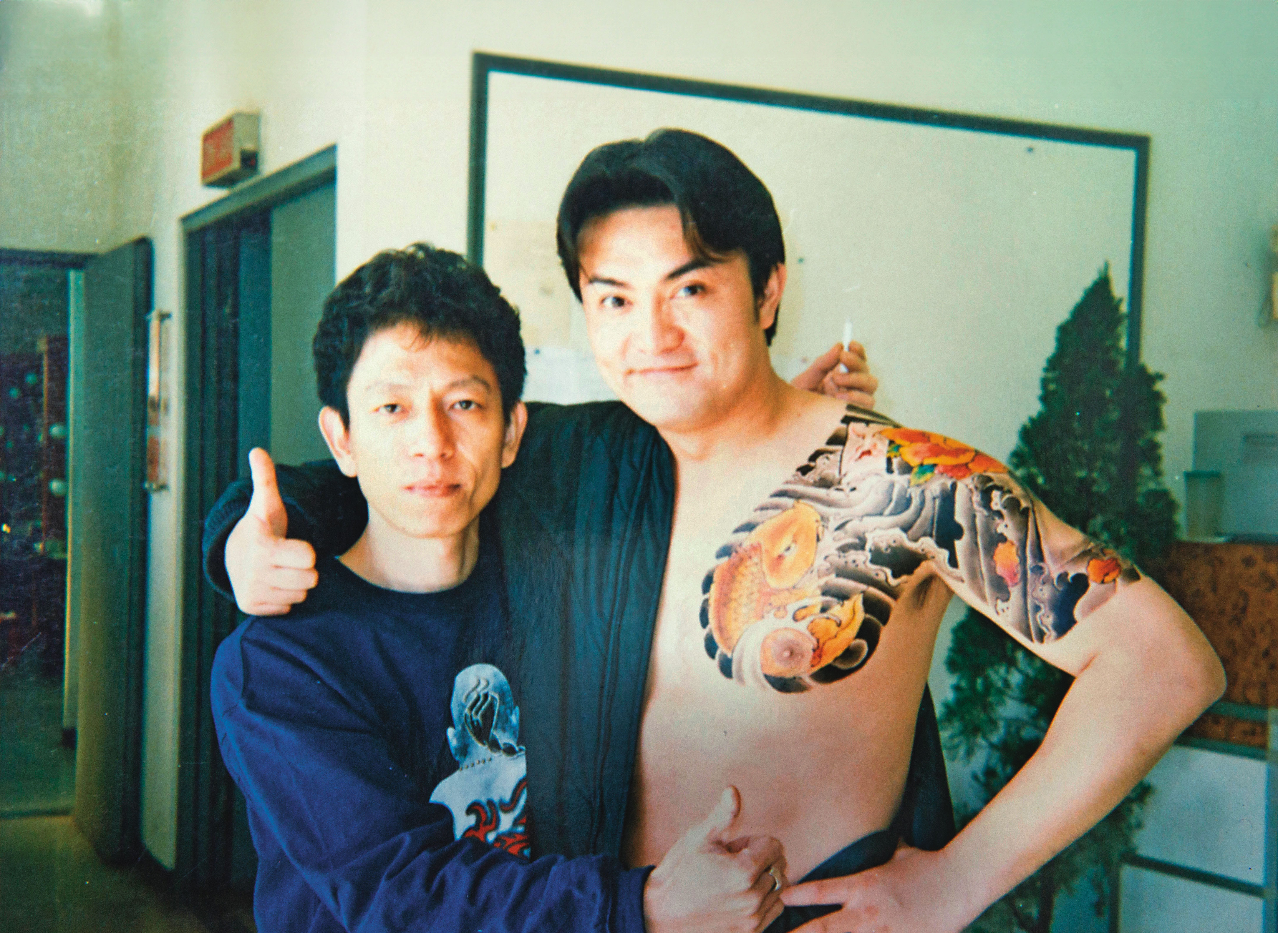 富哥（左）20年前曾到「日正當中」劇組幫藝人李鑼（右）做彩繪。（彫富提供）