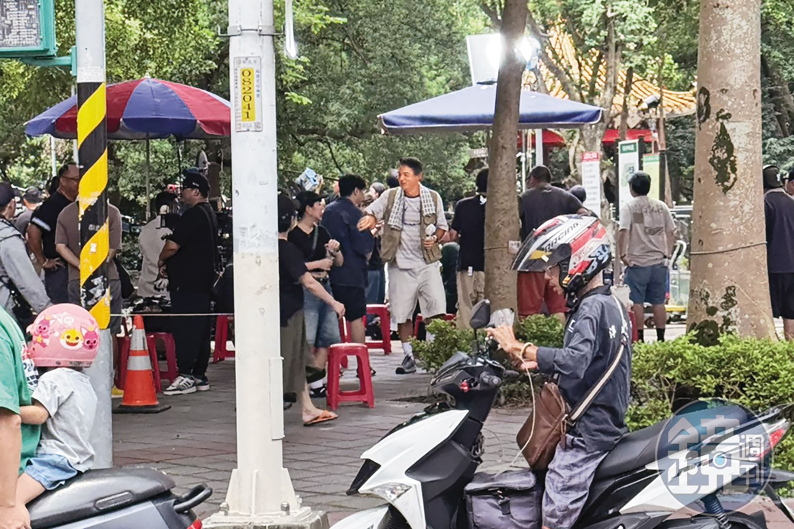 8日中午,李銘順(右)現身新北市永和四號公園一角,他脖子上掛毛巾,手持隨身電風扇,在樹蔭下等候拍攝。(圖/鏡週刊)
