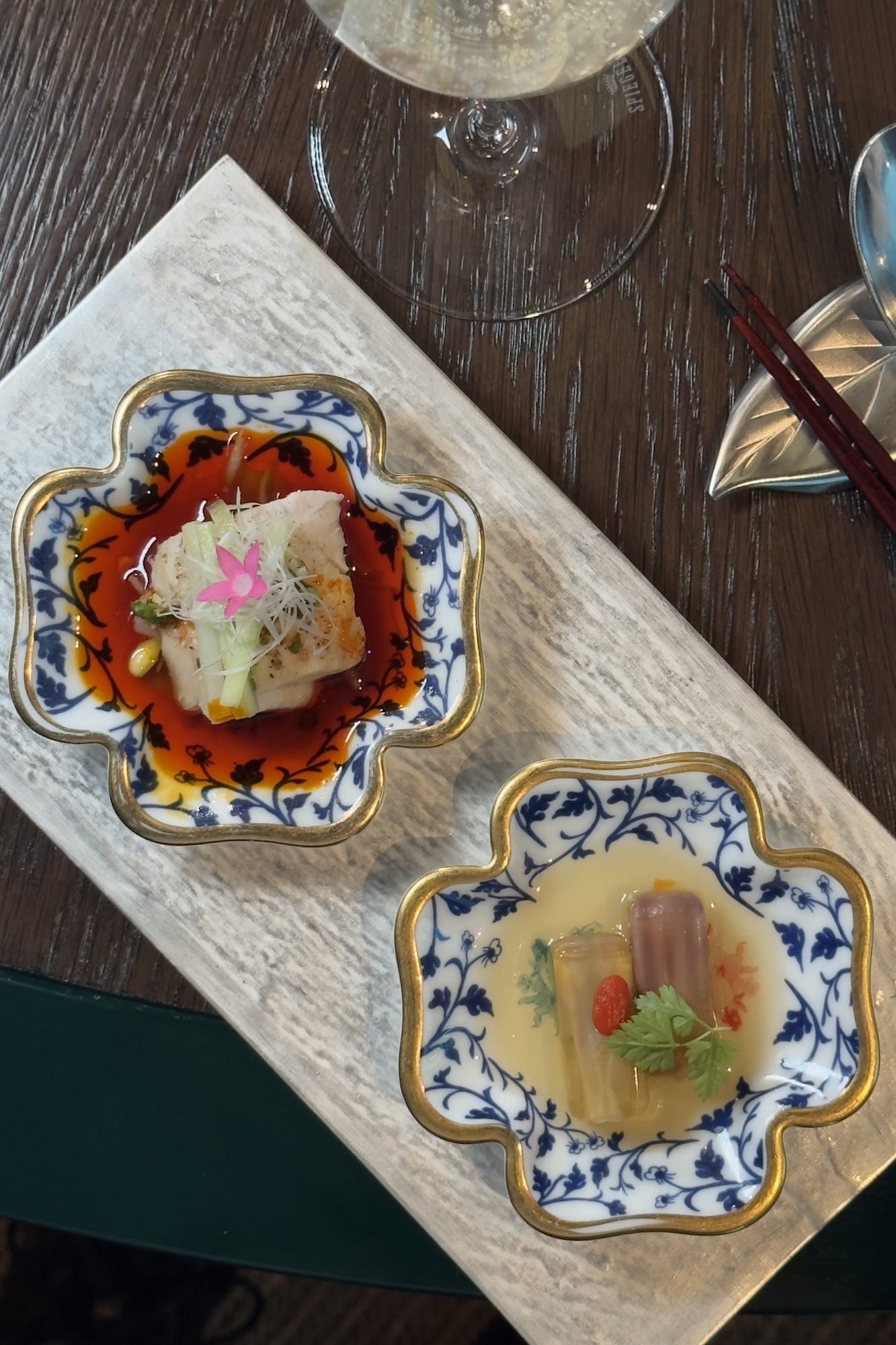 元紀「花雕水晶鴨舌」（下）以花雕酒、當歸等中藥材蒸製鴨舌，手工去骨浸泡一夜，再以高湯凝成清透晶凍，收住酒香與鮮味；鳥苑「口水雞」（上）以低溫烹調桂丁雞胸，搭配融入複方香料、五印醋與日本烏醋的醬汁，再以辣油堆疊酸、辣與辛香。