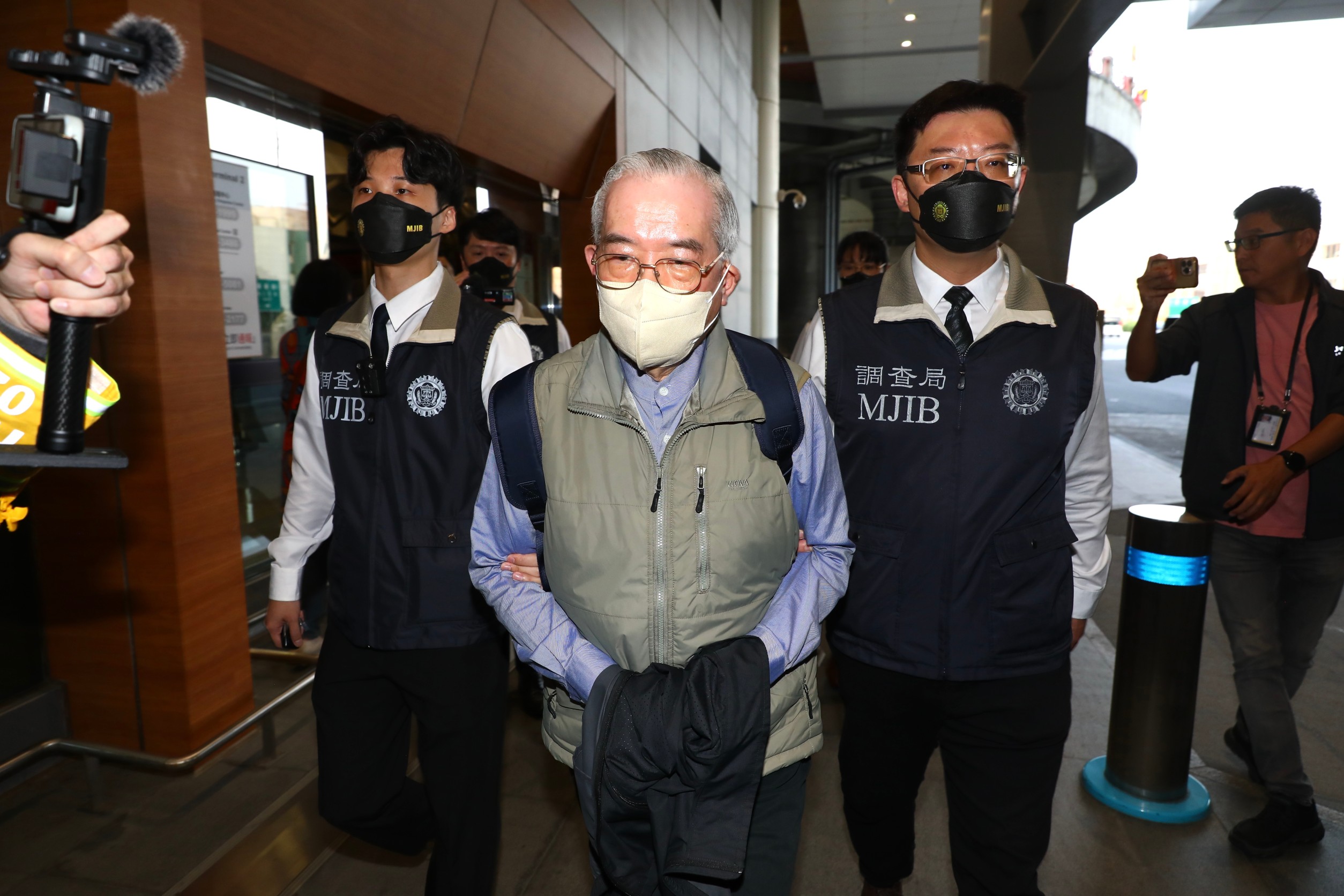 黃立雄（中）抵達桃園機場，台北市調查處接押，後解送北檢歸案。