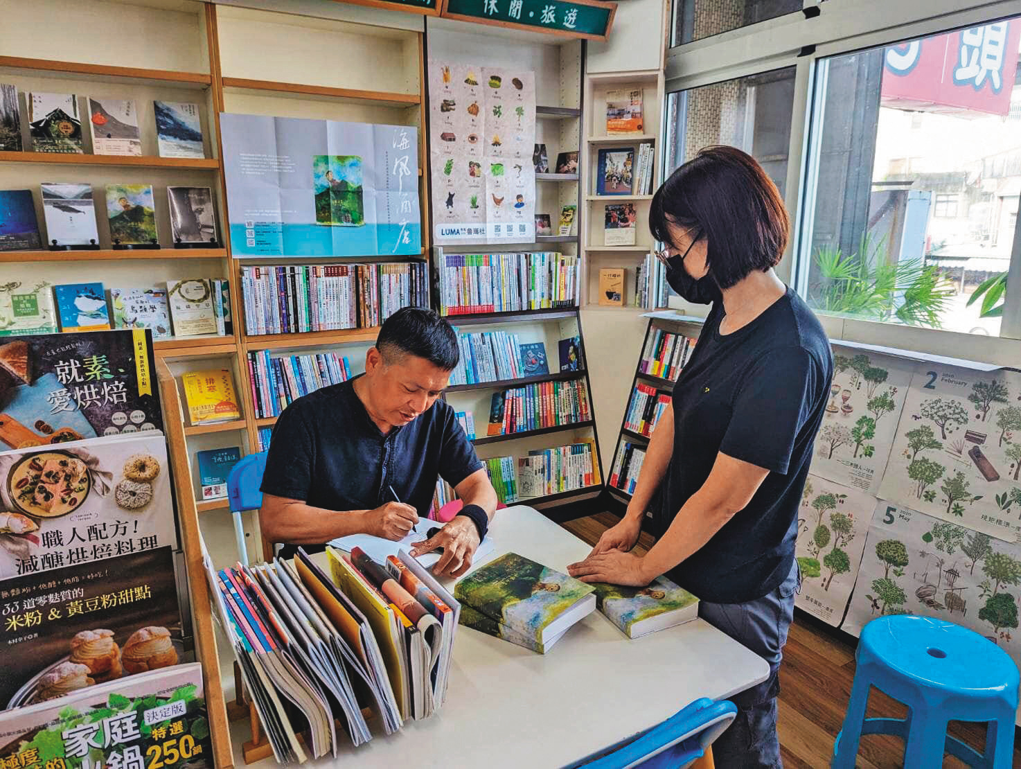 作家吳明益（左）在仁偉書局簽書，氣氛輕鬆。（仁偉書局提供）