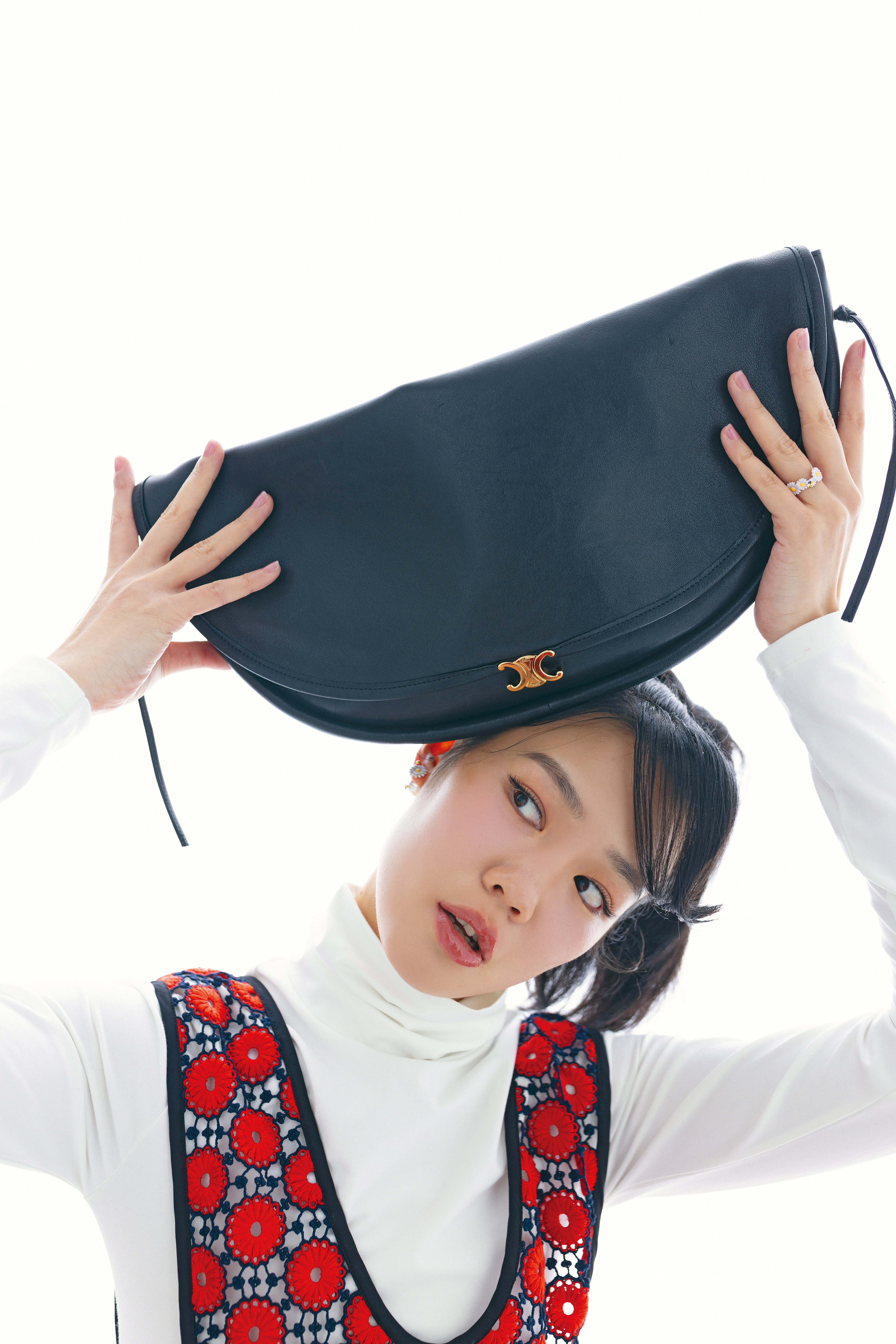 白色高領上衣 NT$29,000 by CELINE、花卉裝飾圍裙 價格店洽by MIU MIU、雛菊耳環NT$19,000 by Dior、雛菊戒指 NT$18,000 by Dior、Halfmoon Soft Triumph亮澤羊皮革手袋 NT$110,000 by CELINE。