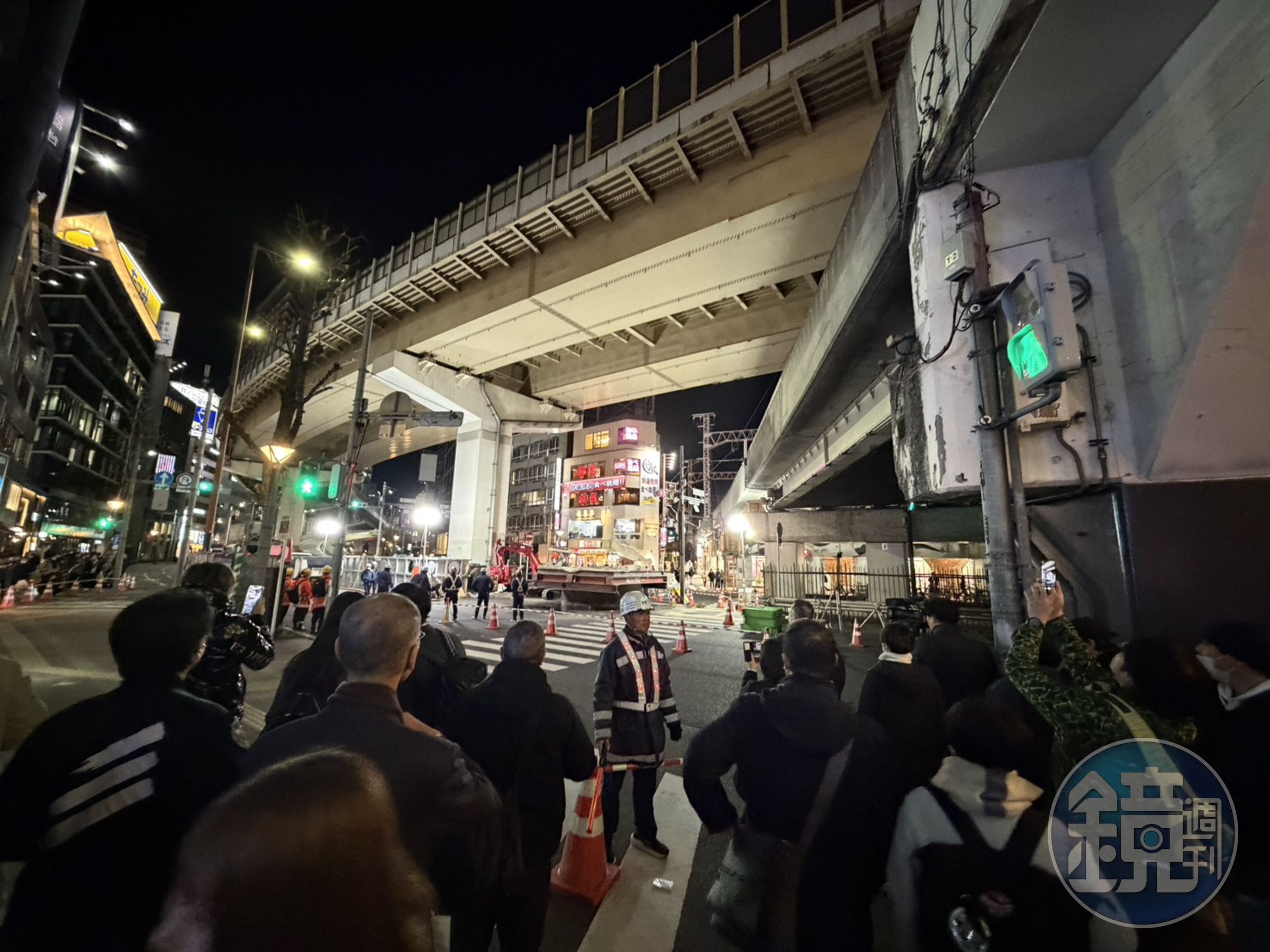 日本大阪梅田路面突然冒出13公尺高巨管,在相關工作人員緊急搶修下,巨管已漸漸下沉。(讀者提供)