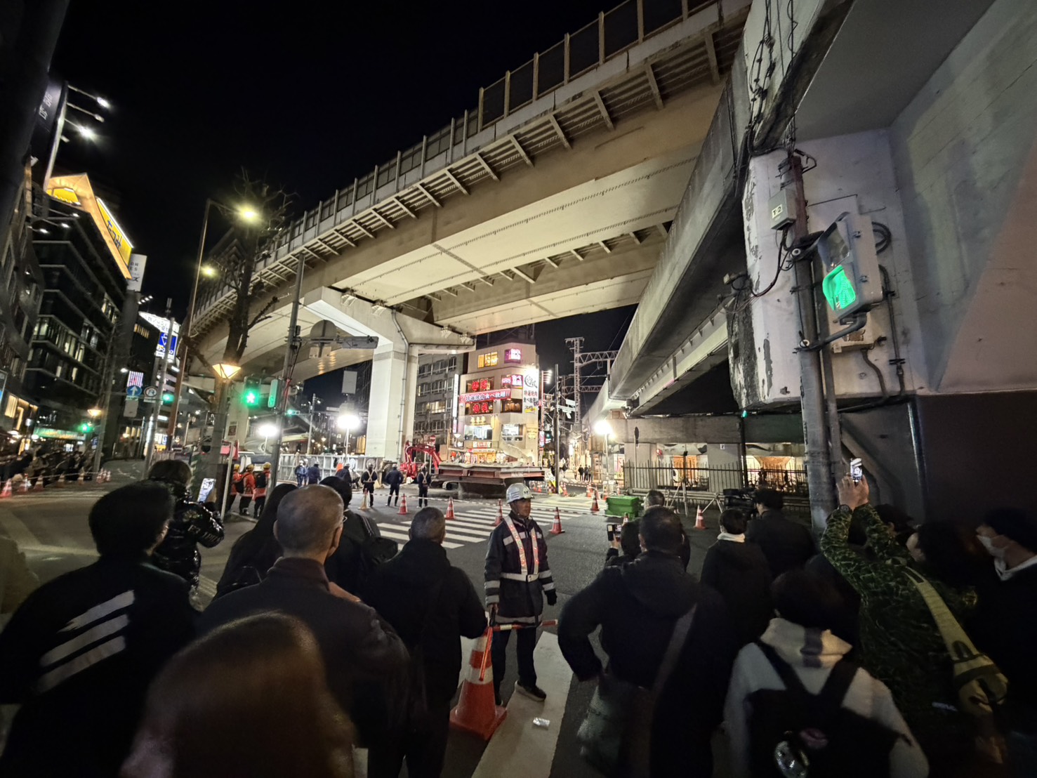 日本大阪梅田路面突然冒出13公尺高巨管，在相關工作人員緊急搶修下，巨管已漸漸下沉。（讀者提供）