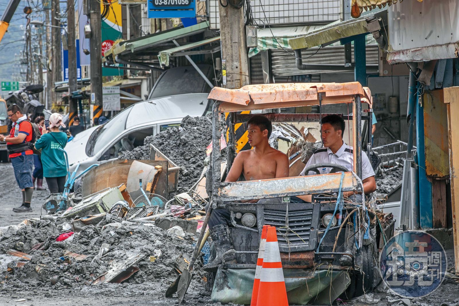 災區道路淤積嚴重，有志工協助清淤之餘，在毀損的車上休息