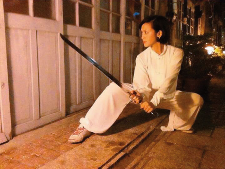 大約10年前,王瀞韓仍希望重拾武術夢。她專長南拳,圖為她身穿武術服、手持南刀。(王瀞韓提供)
