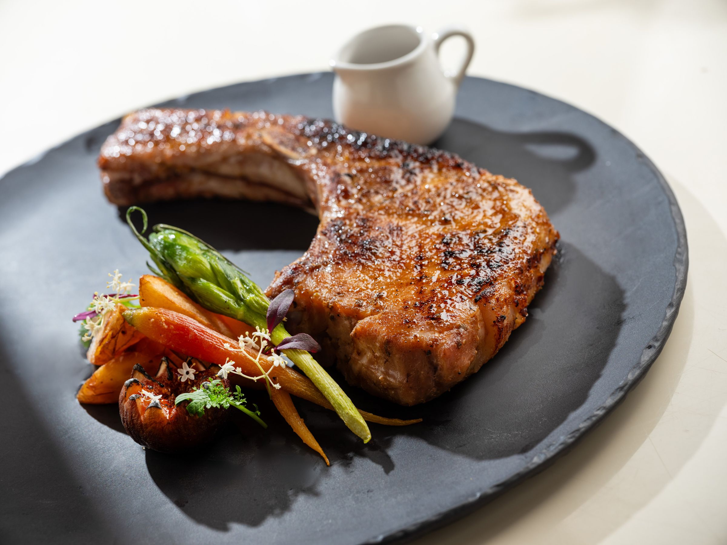 引起肉食者垂涎的12盎司「爐烤葛瑪蘭戰斧豬排」酥嫩多汁,份量感也誠意十足。(1,680元/份,文華東方提供)
